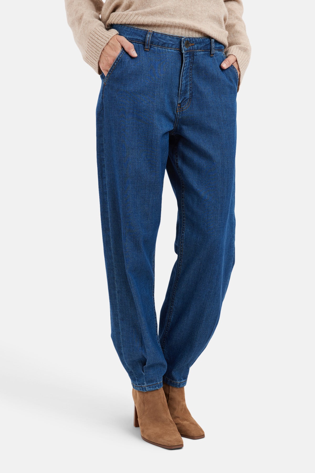 Model wearing tapered barrel-leg jeans paired with a beige sweater and brown ankle boots.