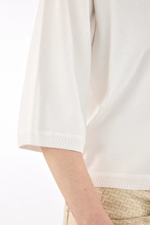 Close-up of a person wearing a white shirt with a neutral background