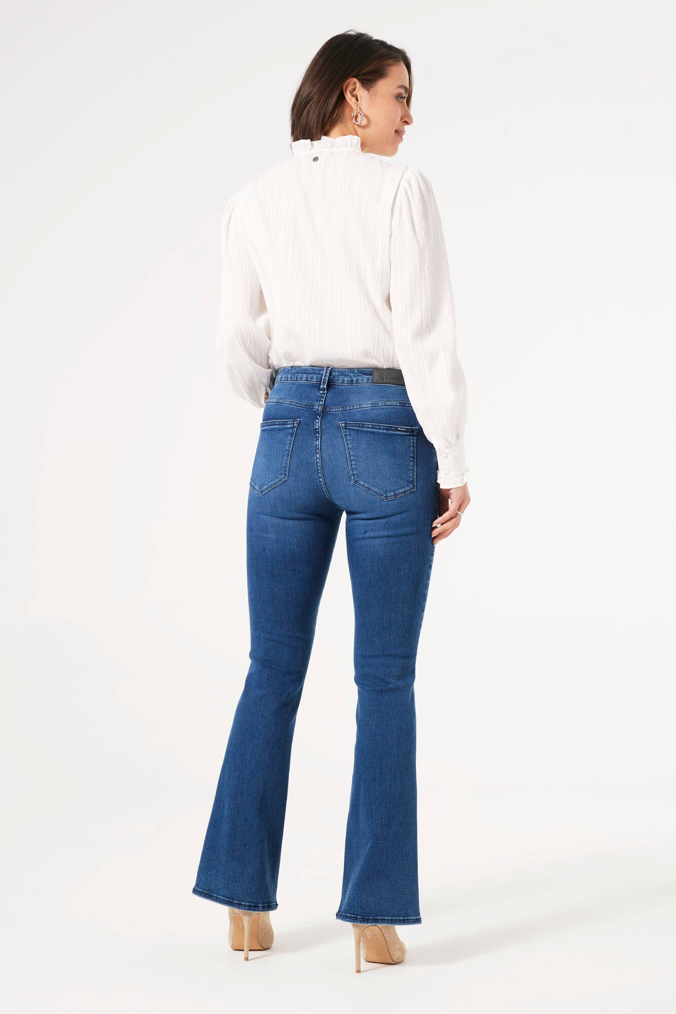 Back view of women's blue flare jeans featuring a mid-rise waist, classic back pockets, and a slim fit through the leg with a gentle flare.