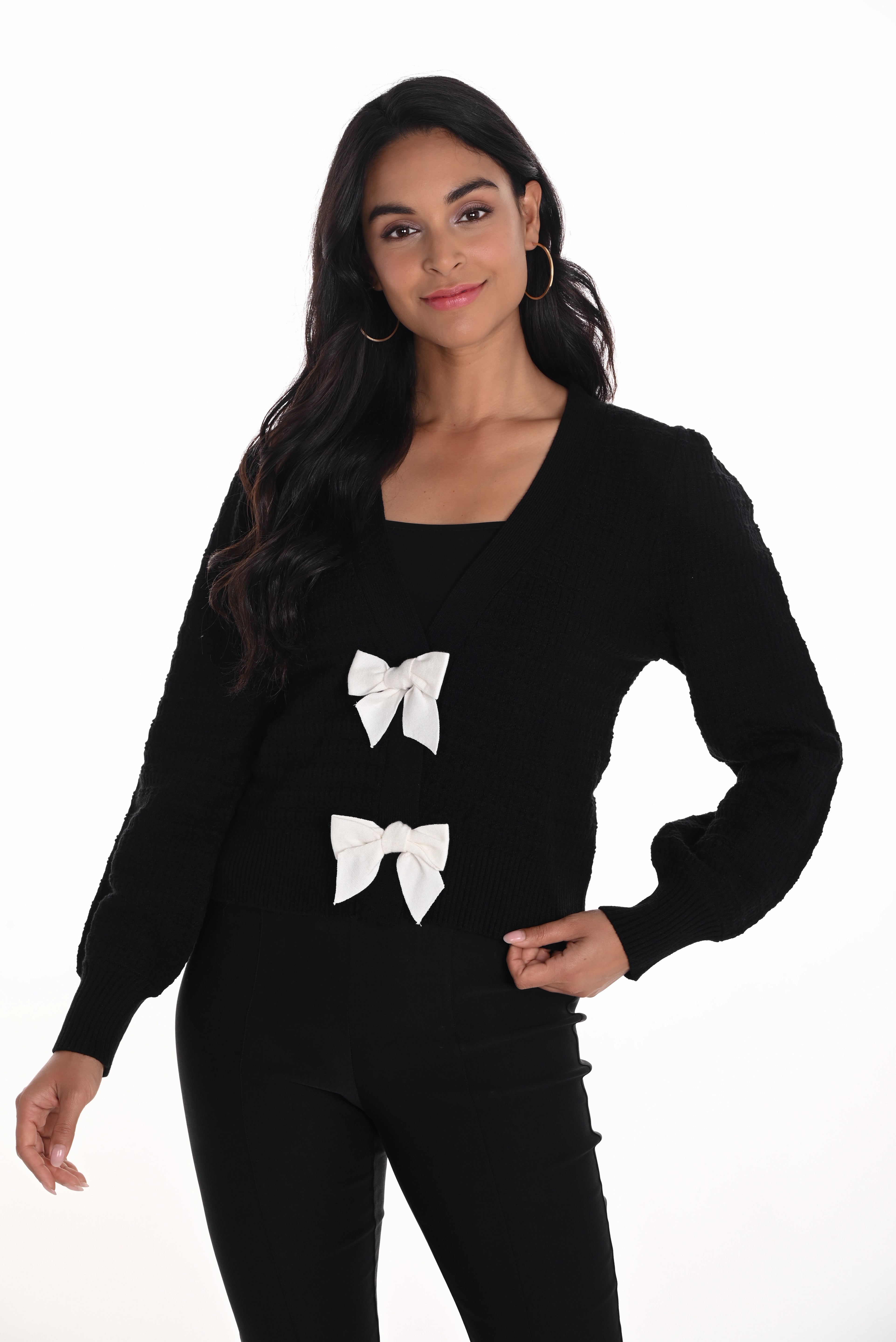 Woman wearing a black sweater with white bow designs on a white background