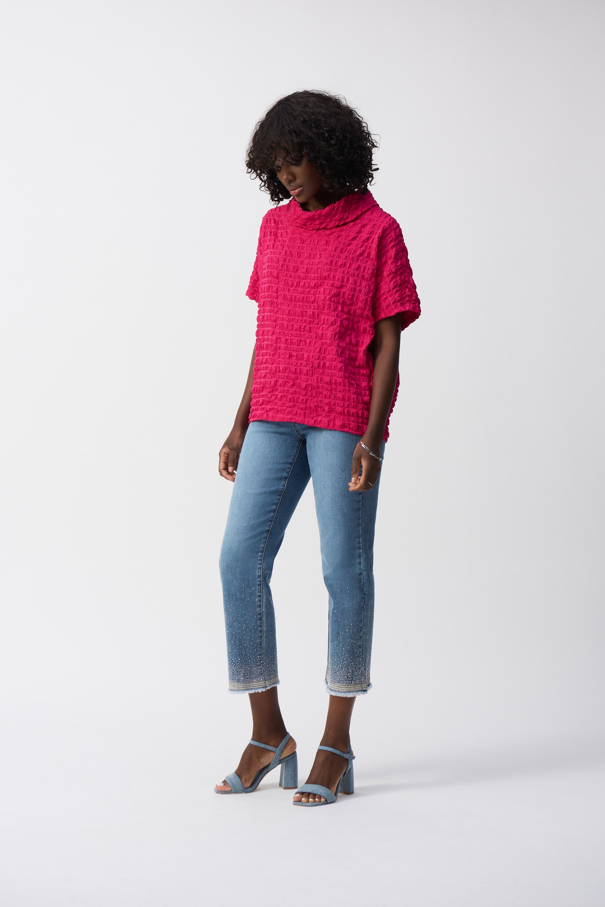 Full body shot of model in hot pink textured top and cropped jeans with crystal-embellished hem and frayed edges.