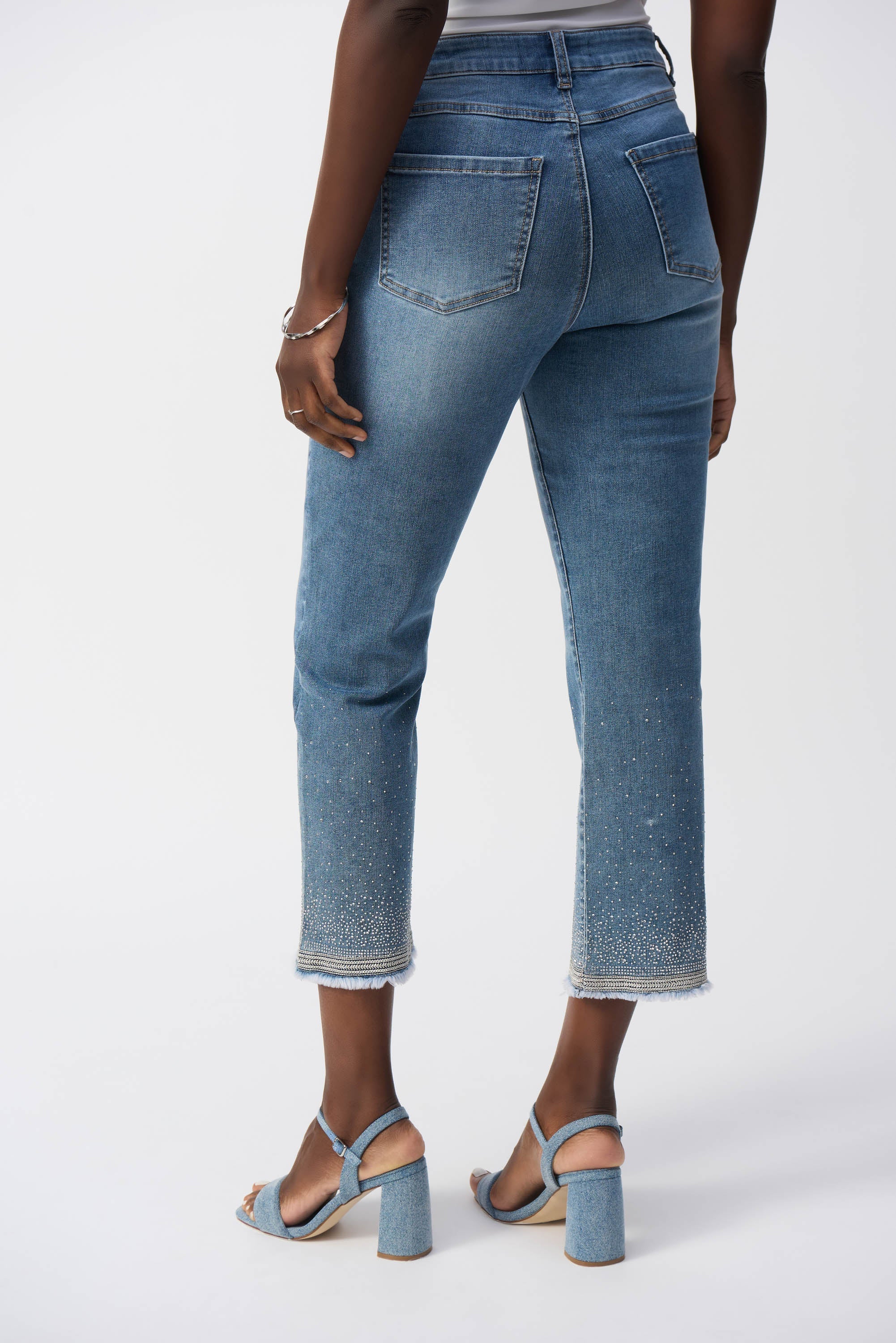 Rear view of model wearing cropped straight jeans with light fading and crystal-detailed hem.