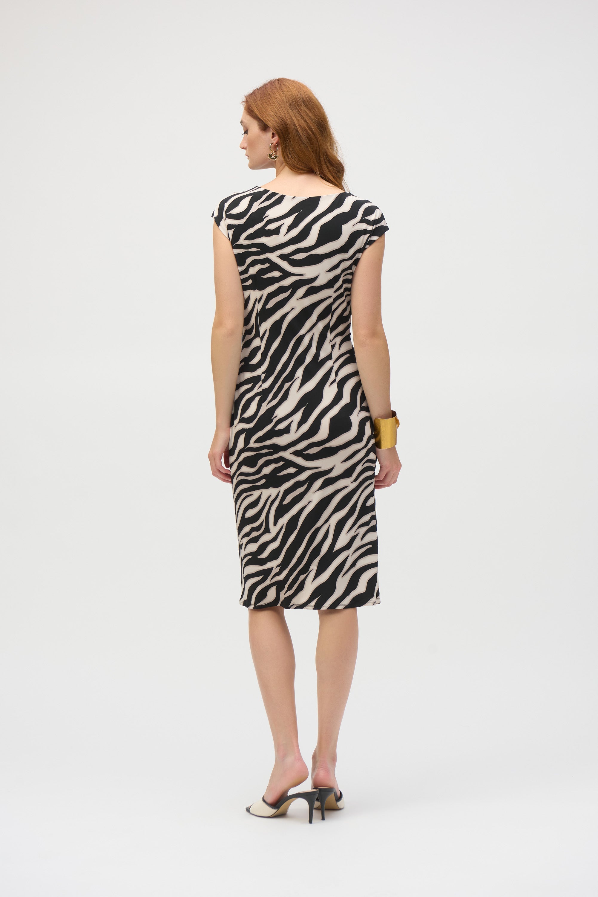 Back view of woman in zebra print dress showing fitted silhouette and cap sleeves.