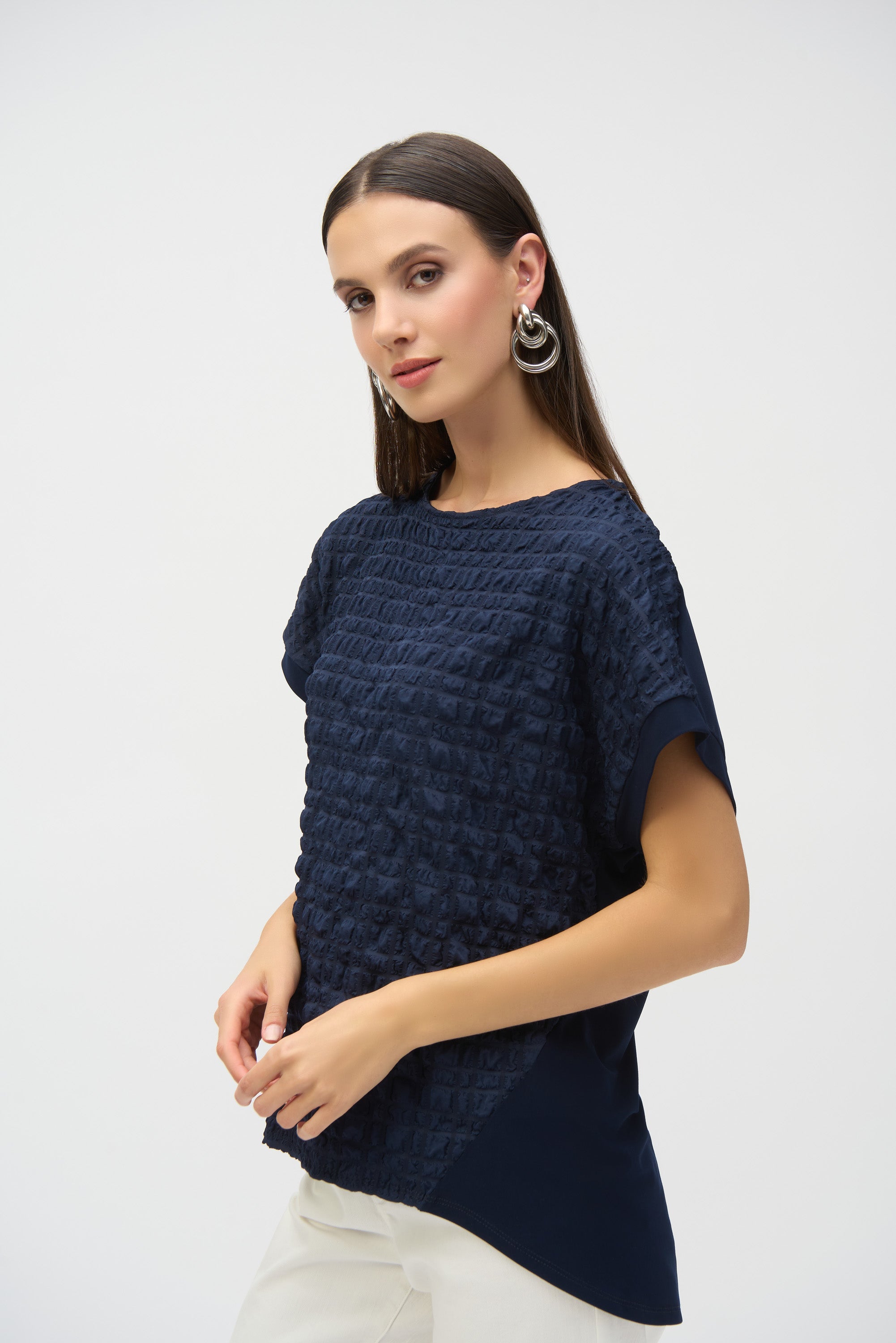 Side view of woman wearing navy textured top, showing layered texture on front and smooth paneling on side.