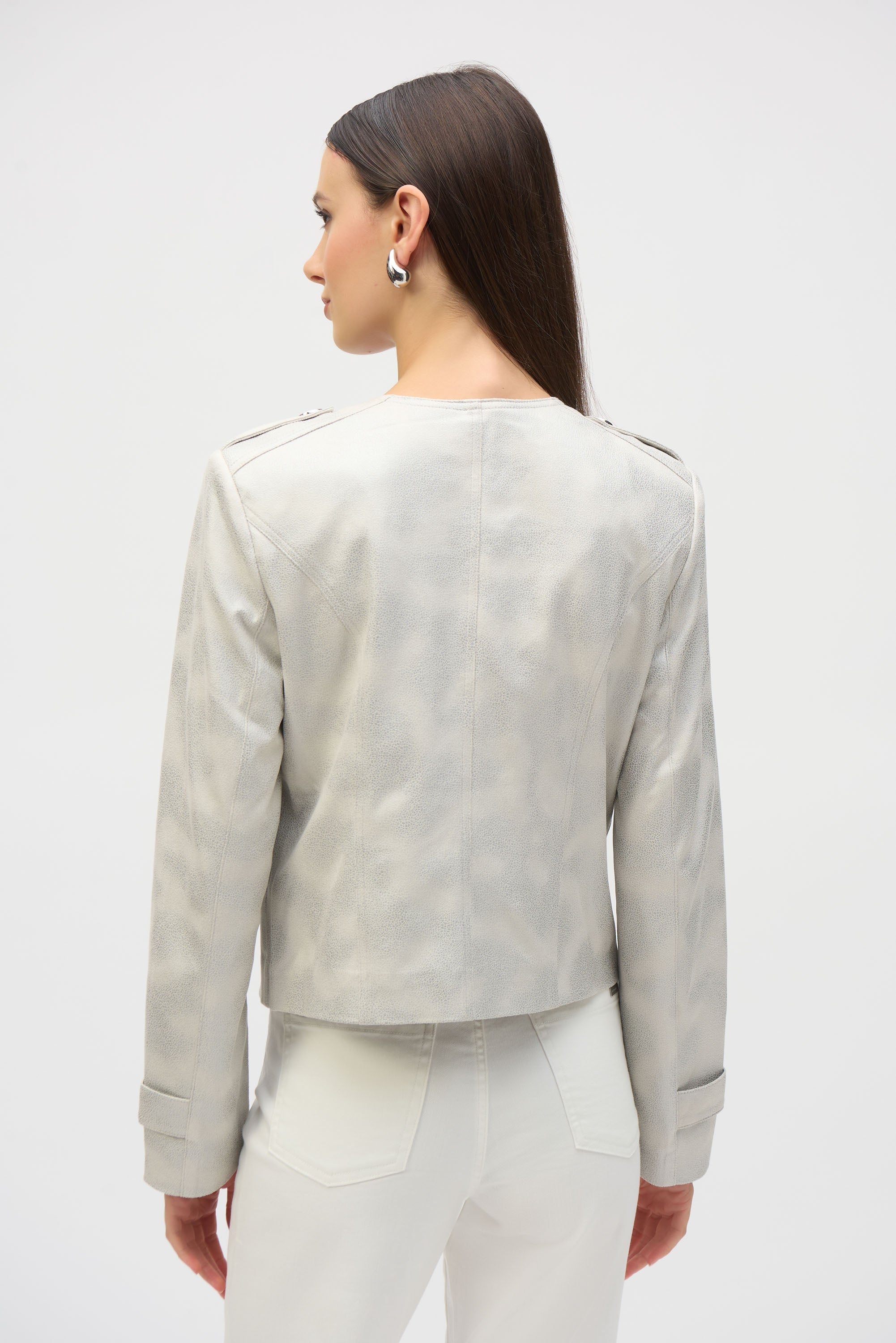 Woman wearing ivory foiled faux suede jacket with shoulder tabs, shown from the back with long straight hair.