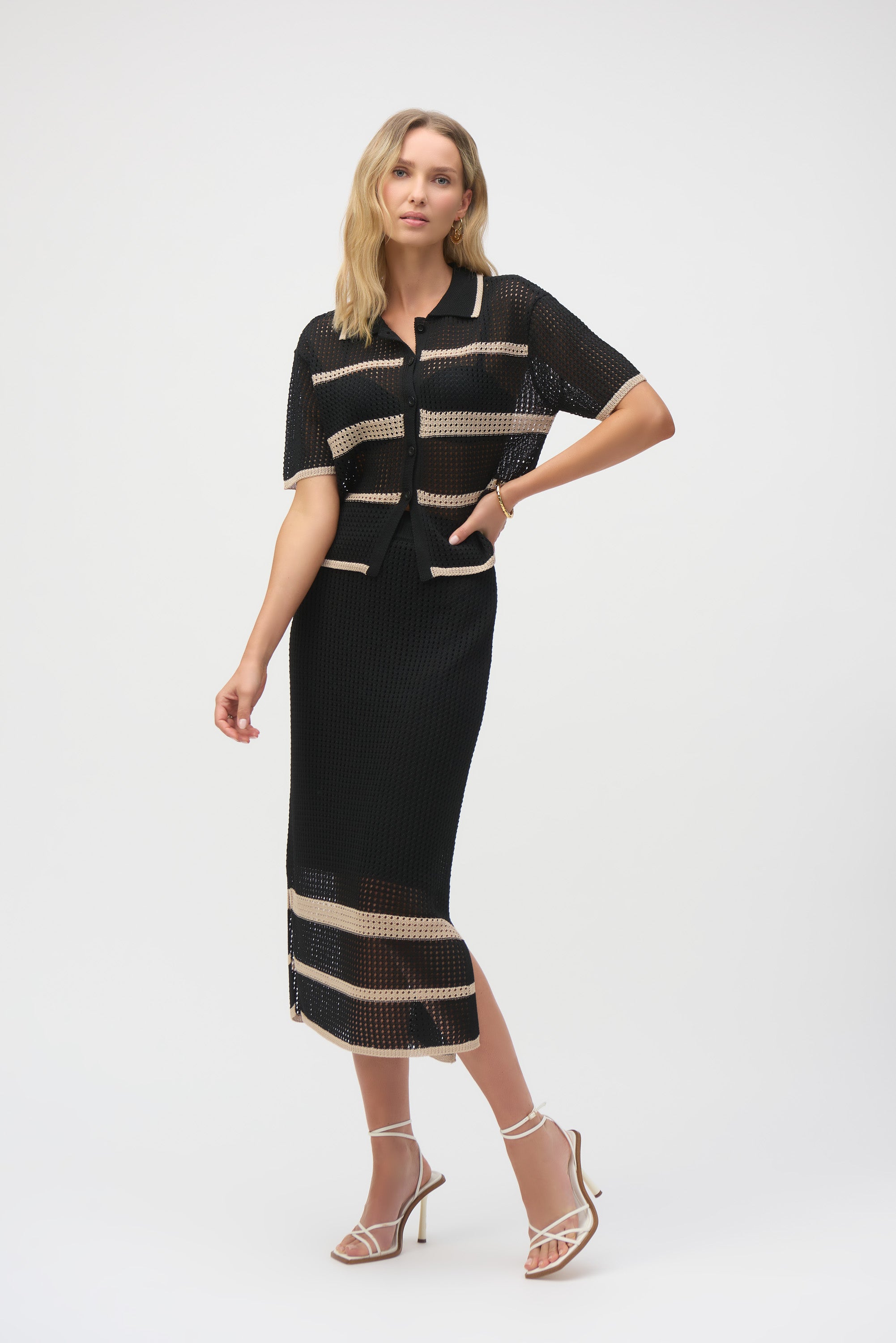 Woman wearing matching black and beige striped open-stitch knit set, including short-sleeve cardigan and midi skirt.