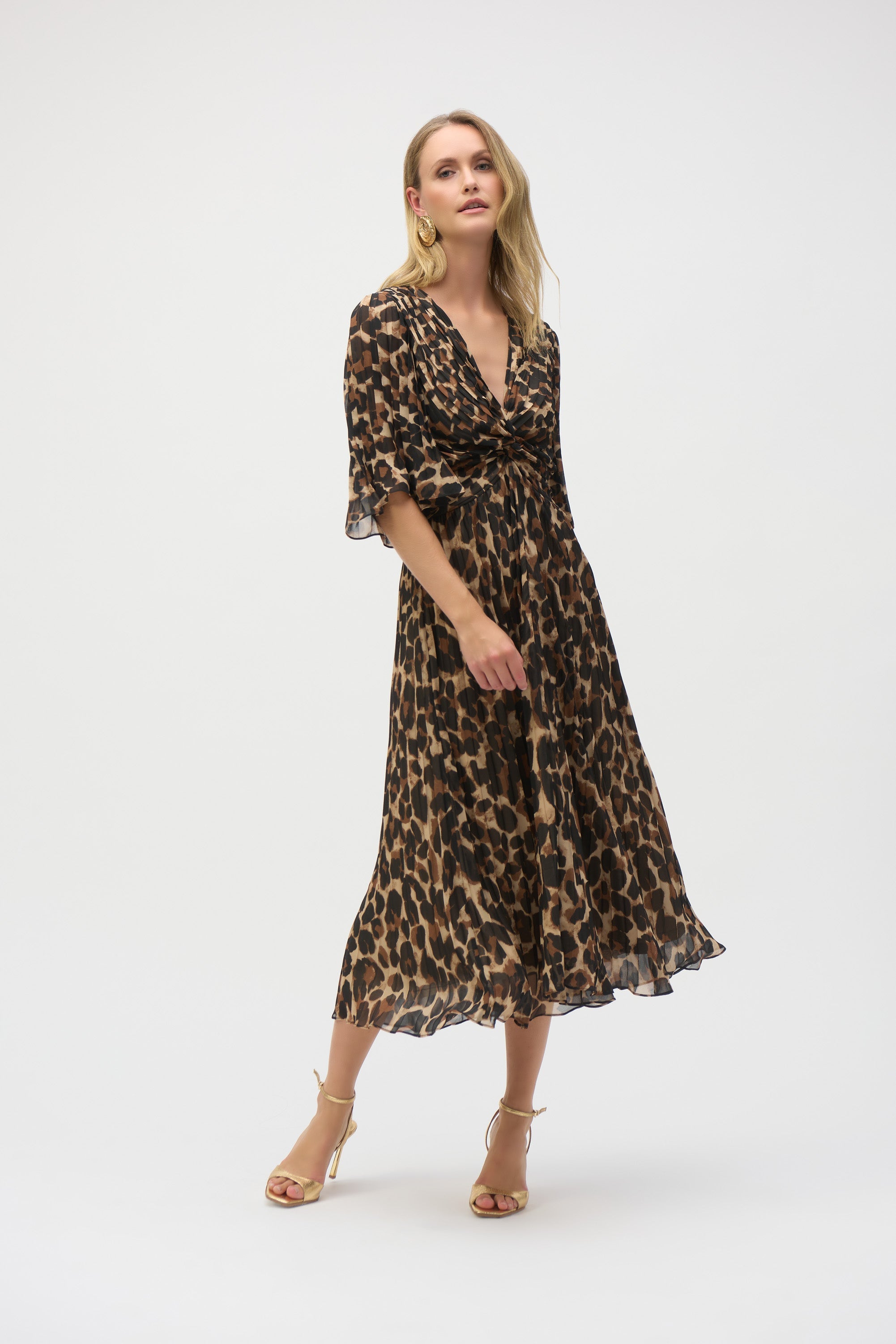Woman wearing leopard print chiffon fit-and-flare midi dress with flared sleeves and gold heels, walking forward.