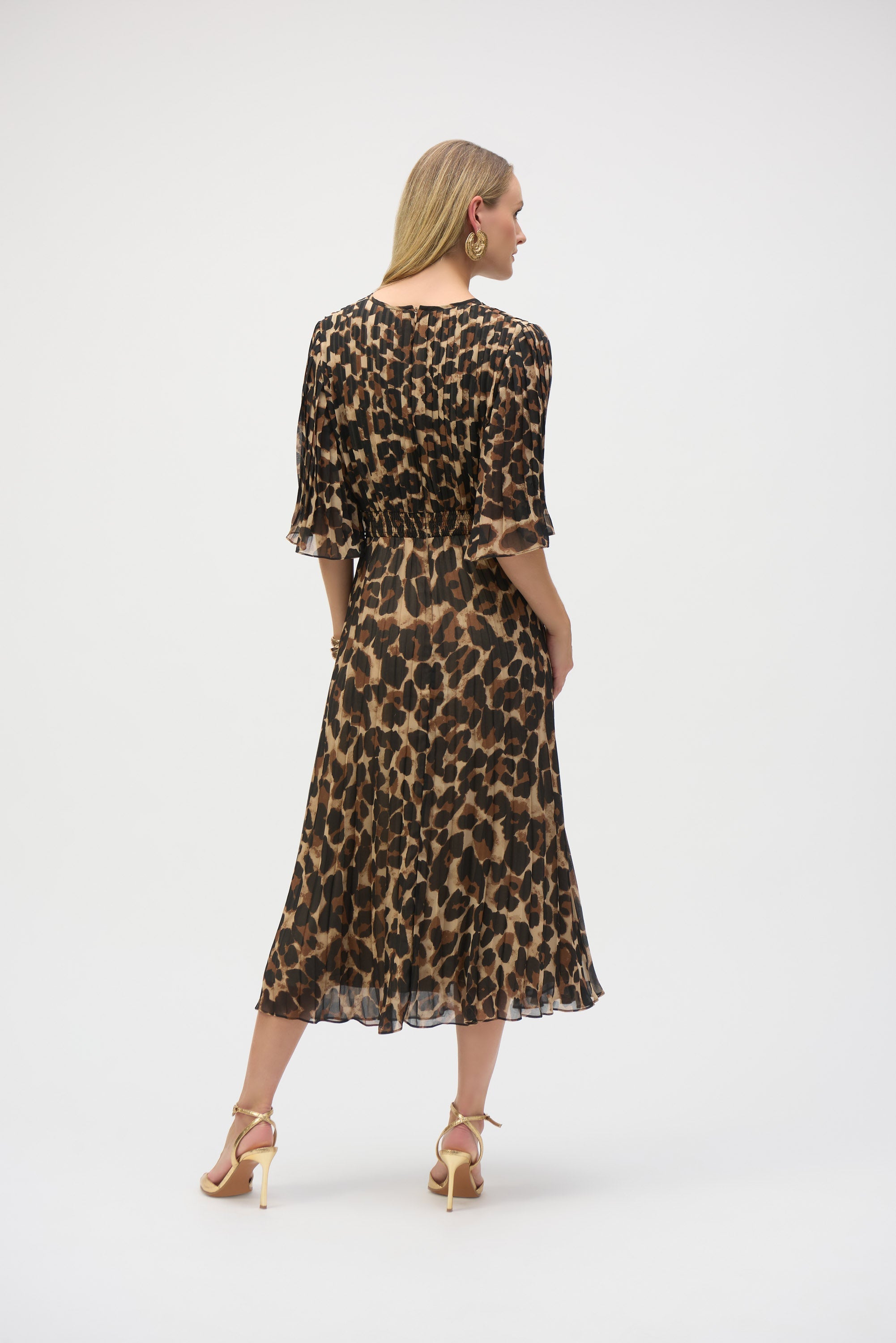 Woman wearing animal print chiffon midi dress with flared short sleeves and smocked back waistband, shown from behind.