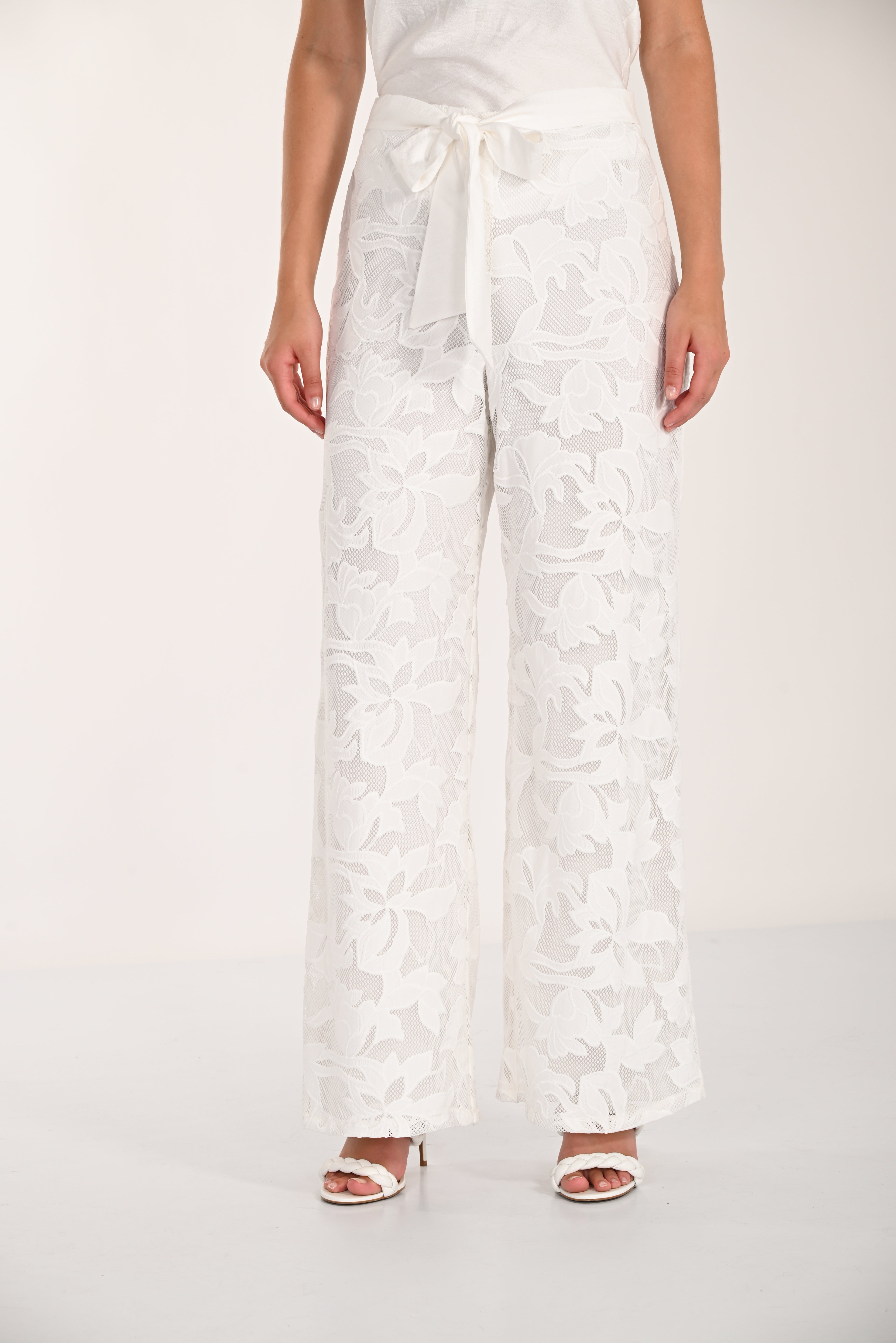 Close-up front view of floral lace wide-leg pants with a self-tie waistband and wide-leg design.