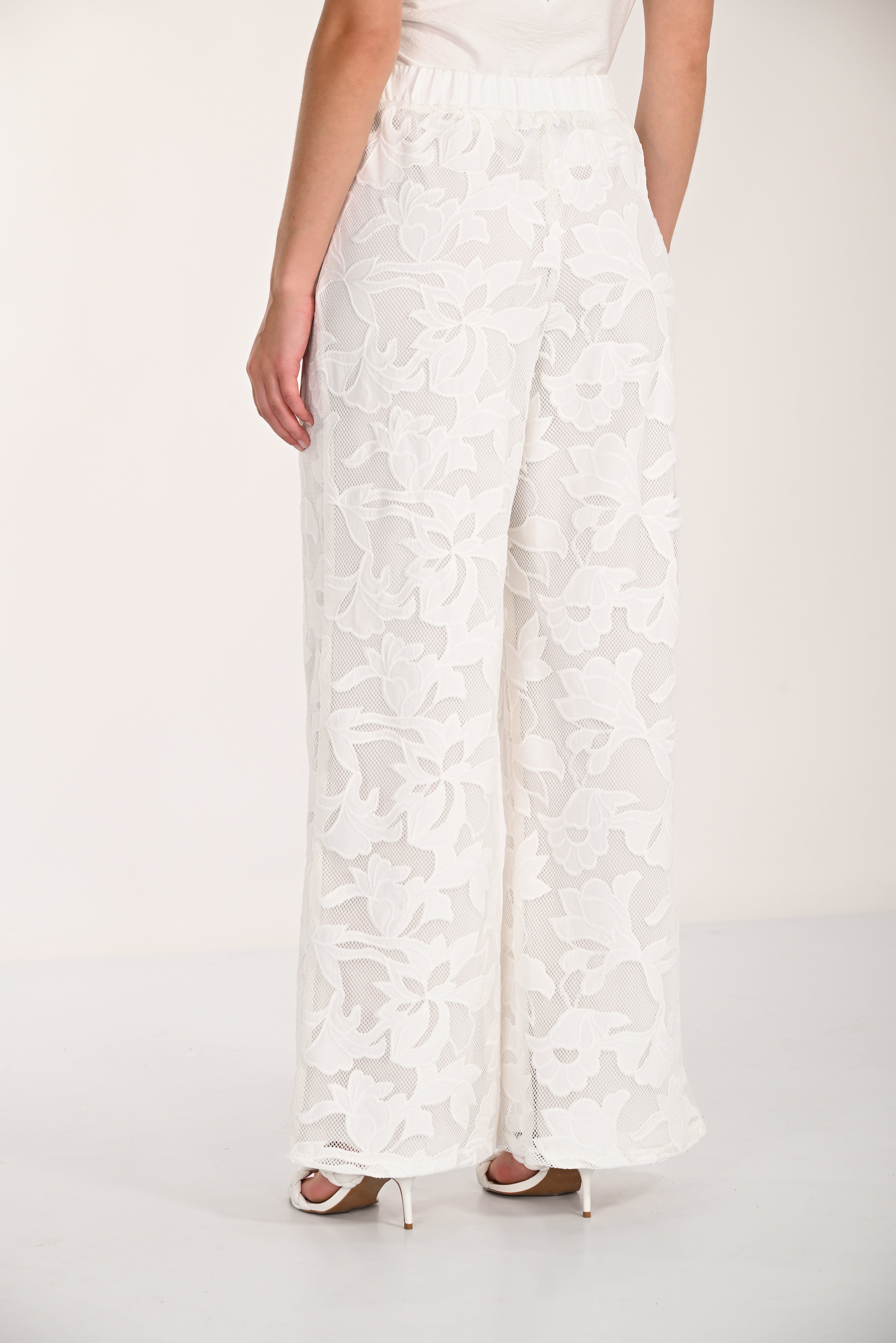 Back view of floral lace wide-leg pants featuring a relaxed fit and flowing silhouette.