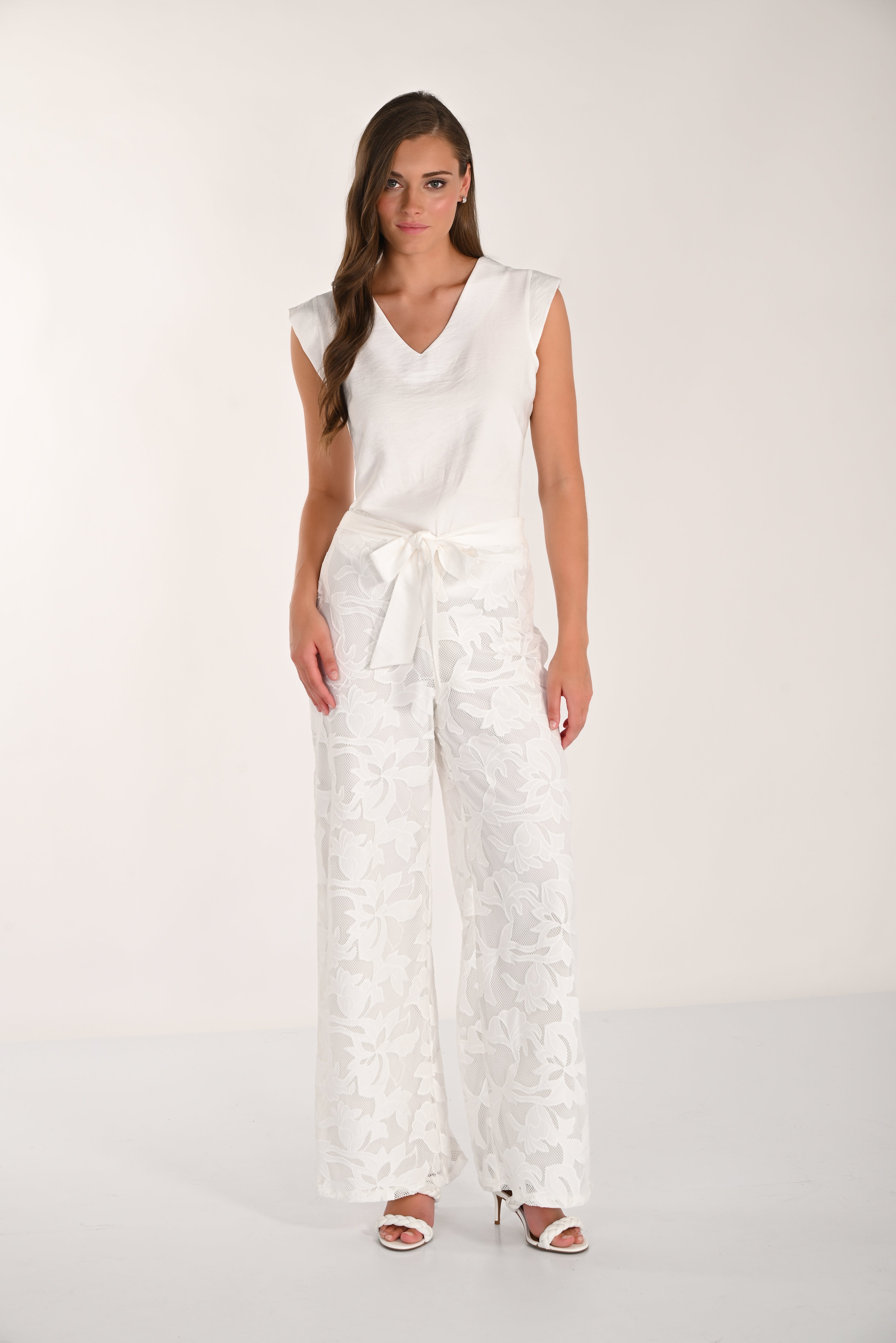 Model wearing floral lace wide-leg pants with a sleeveless V-neck top and heeled sandals, front view.