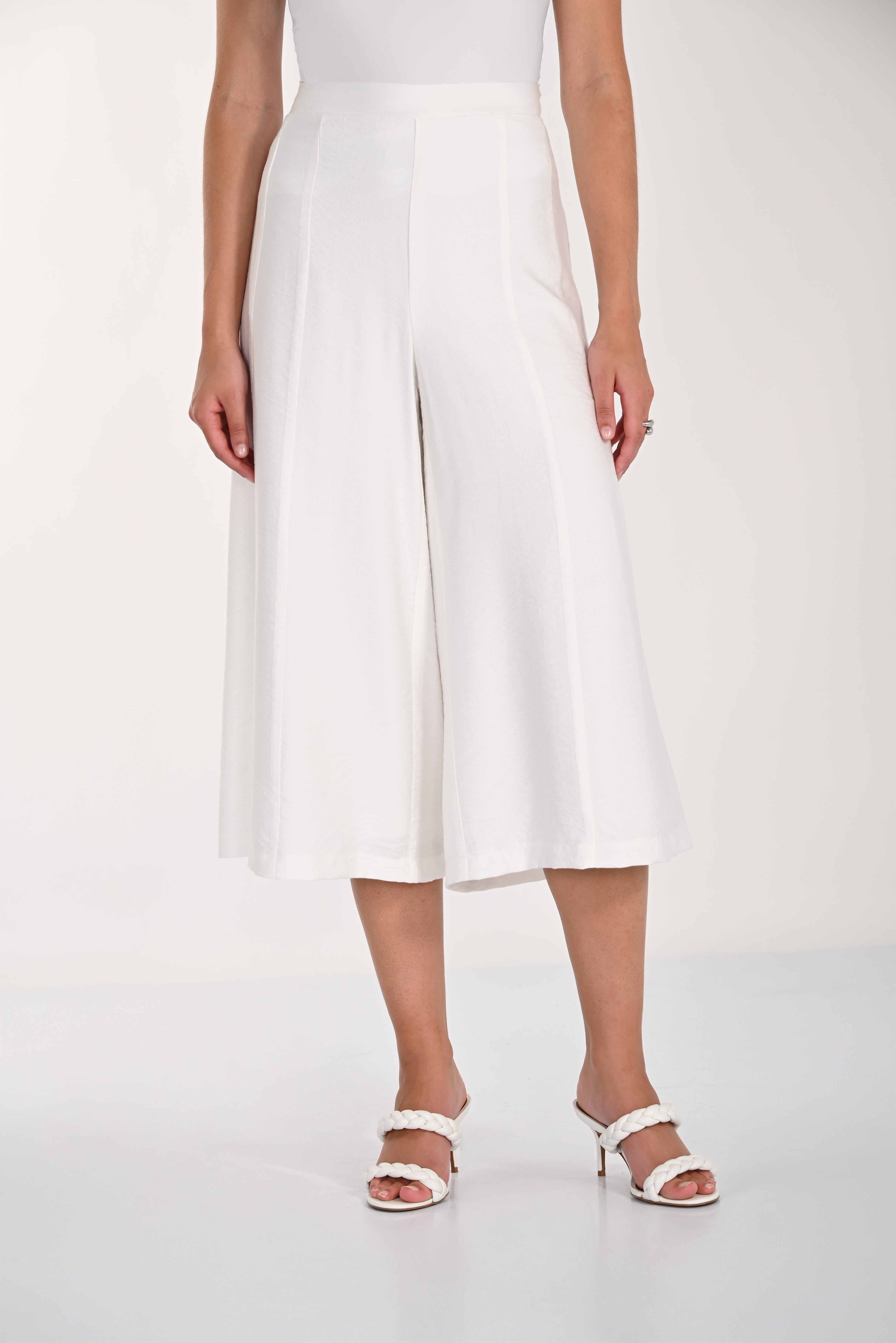 Back view of white wide-leg culotte pants with an elasticized waistband and flowy cropped silhouette.