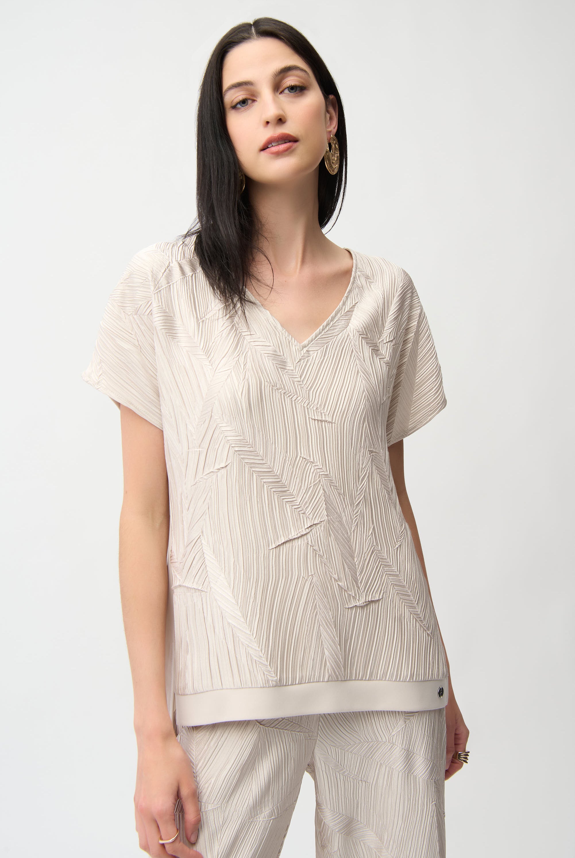 Pleated Satin V-Neck Top in light beige with textured geometric pleats and relaxed dolman sleeves, showcasing elegance.