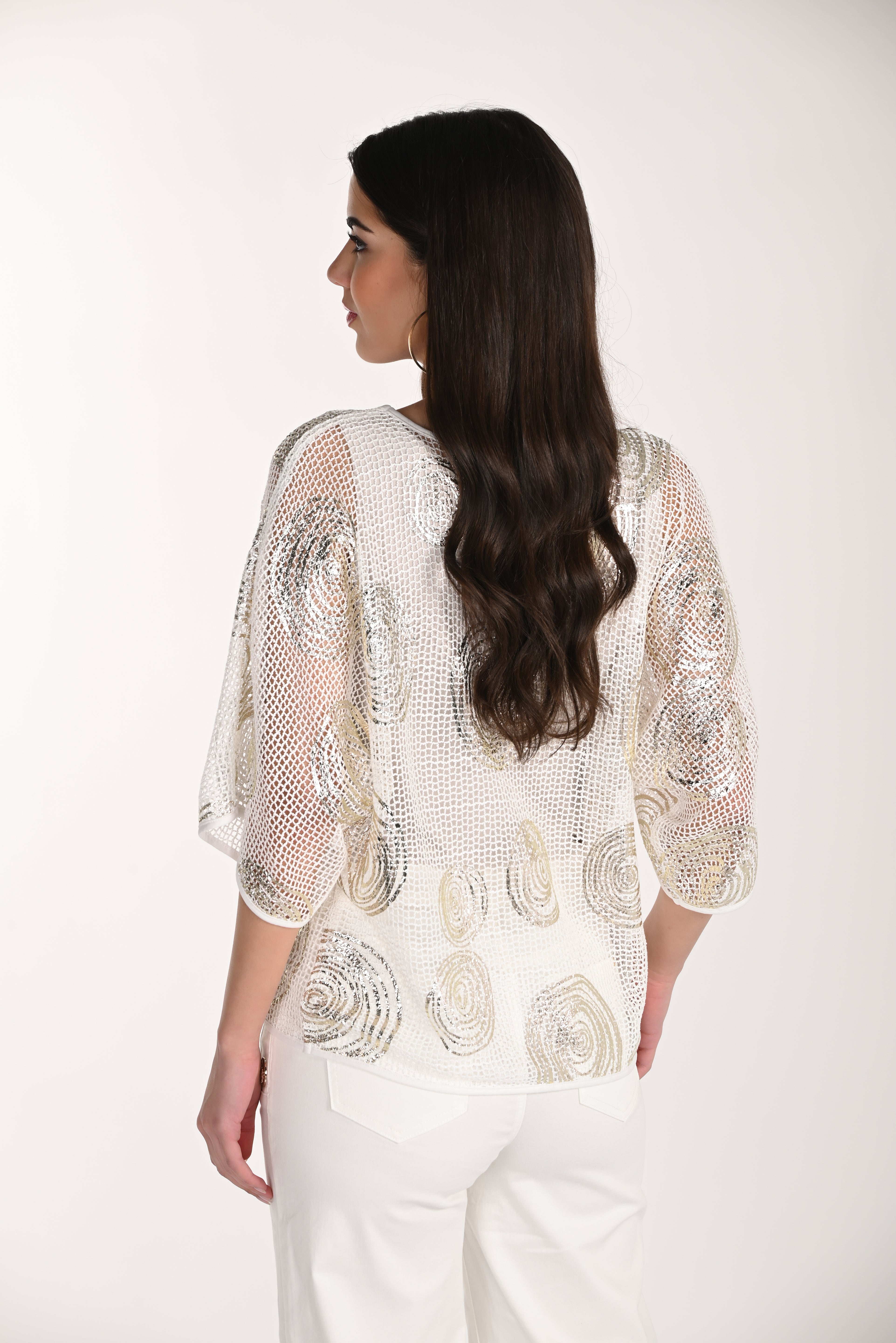Model wearing a sequin mesh overlay top with metallic sequin embellishments and relaxed kimono-style sleeves.