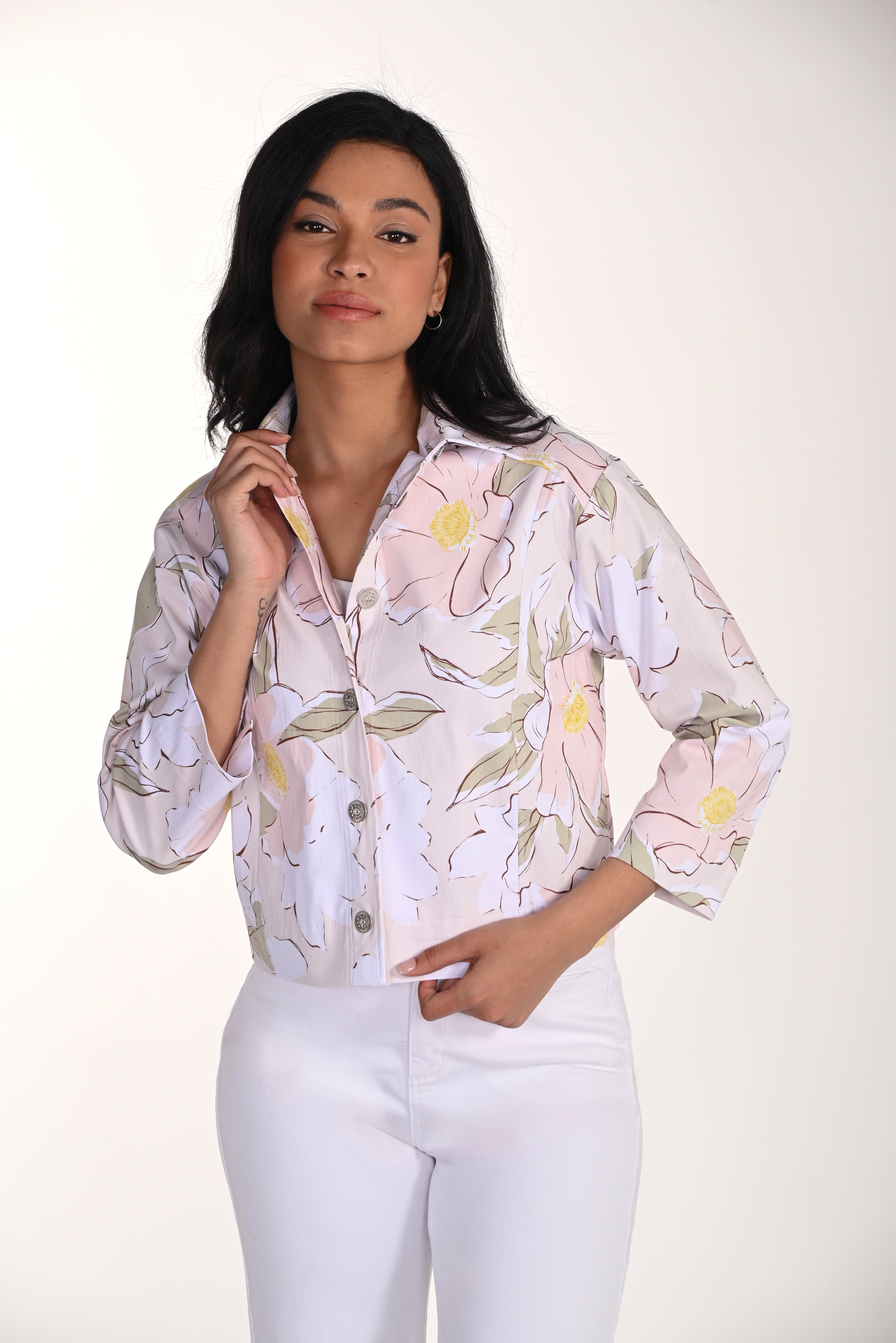 woman wearing a soft pink floral cropped jacket with button-front detail and white pants.