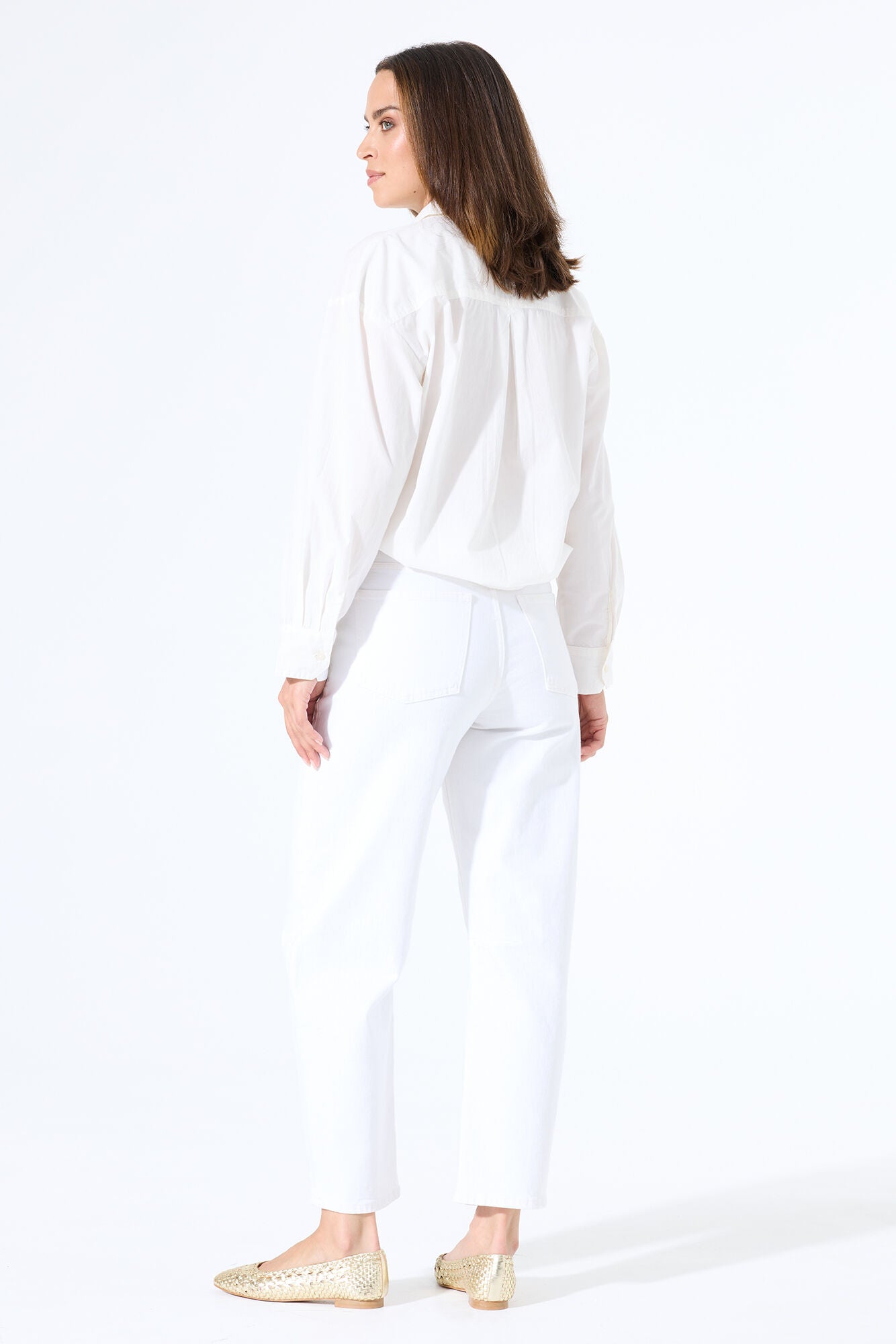 Model wearing white barrel-leg denim jeans with a button-up shirt tucked in, styled with flats for a clean, polished outfit.
