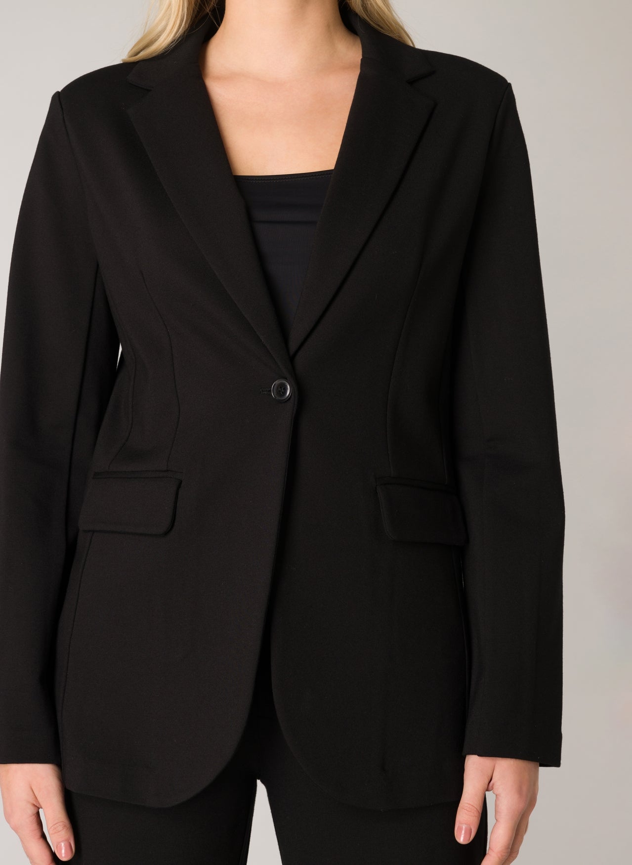 Front close-up of a black women's tailored blazer featuring a notch lapel, single-button closure, and front flap pockets.