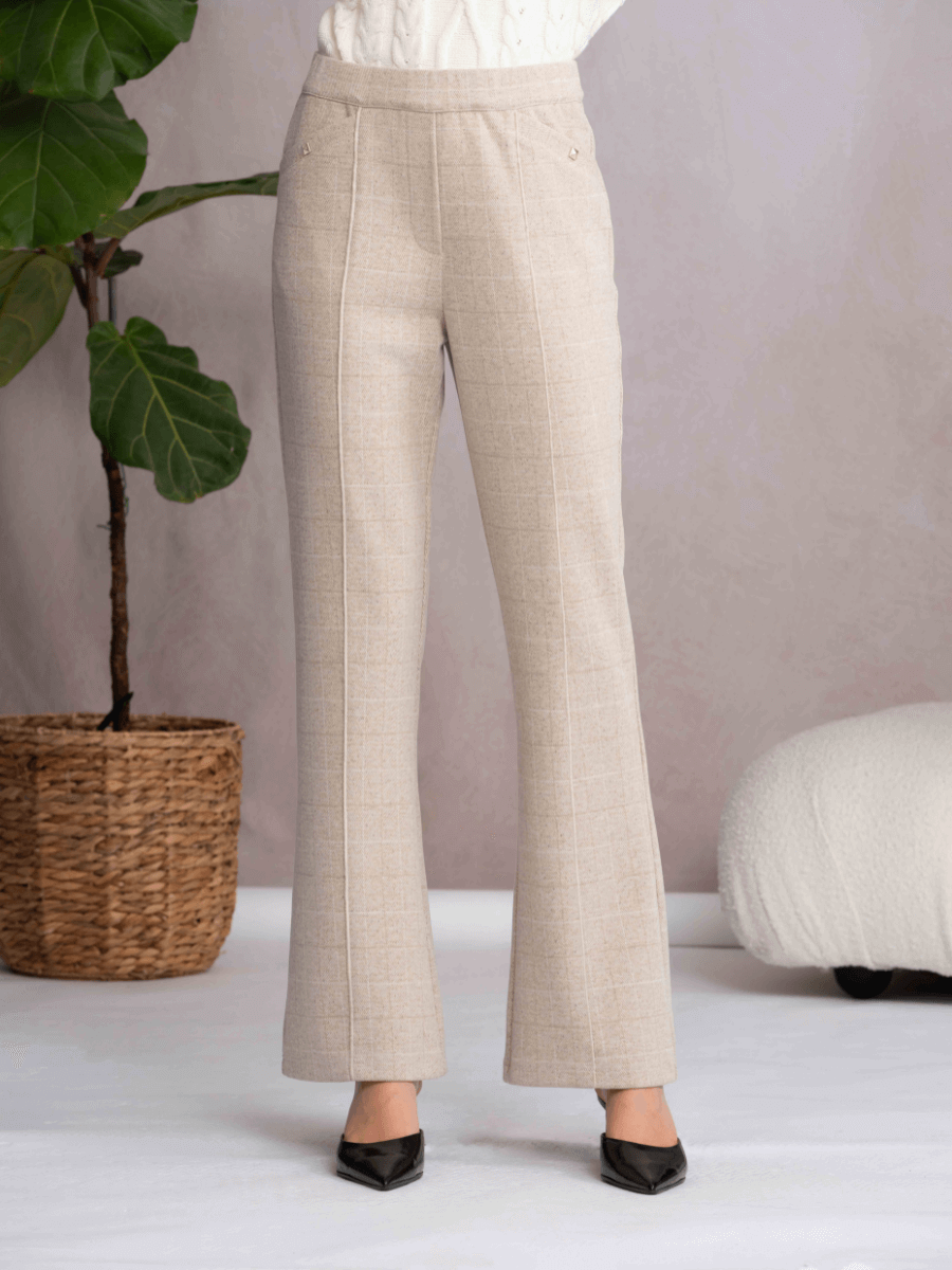 Beige pants worn by a person with a plant and white cushion in the background