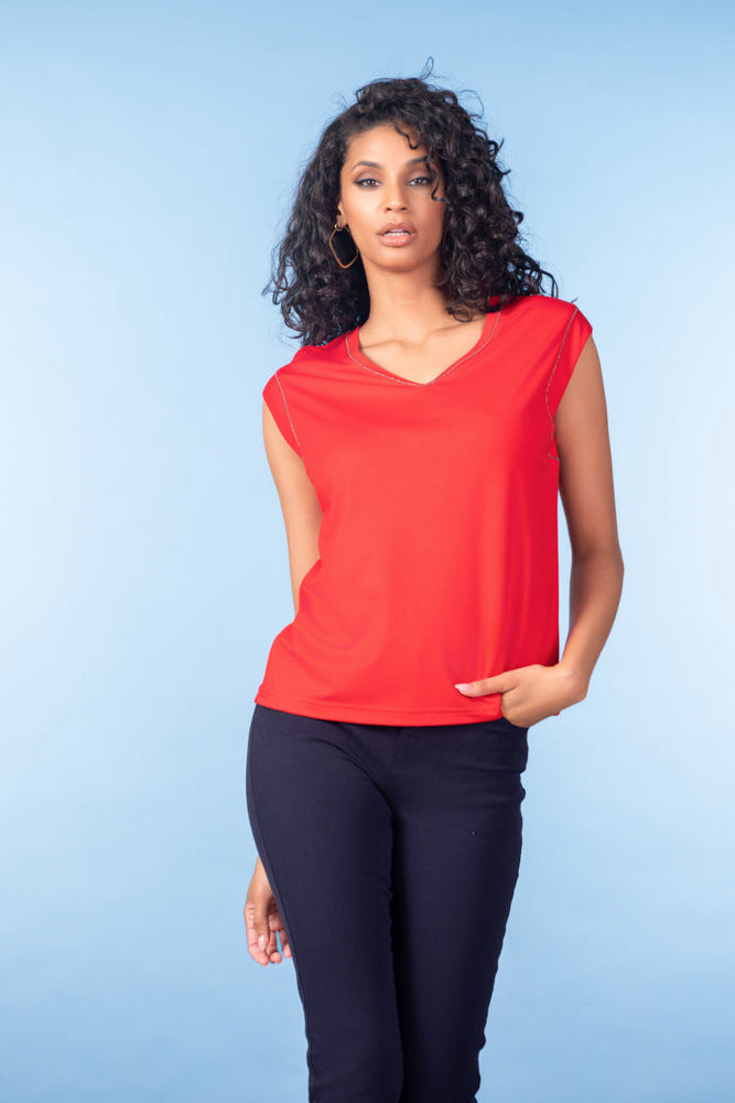 Woman wearing a red sleeveless top and black pants against a blue background