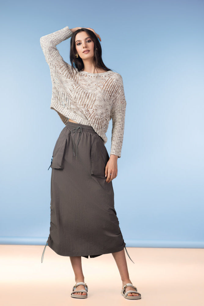 Woman wearing a patterned sweater and gray skirt against a blue background