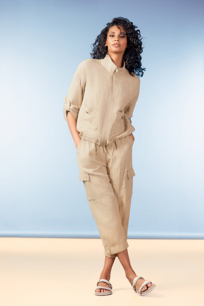 Woman wearing a beige outfit with cargo pants against a blue background