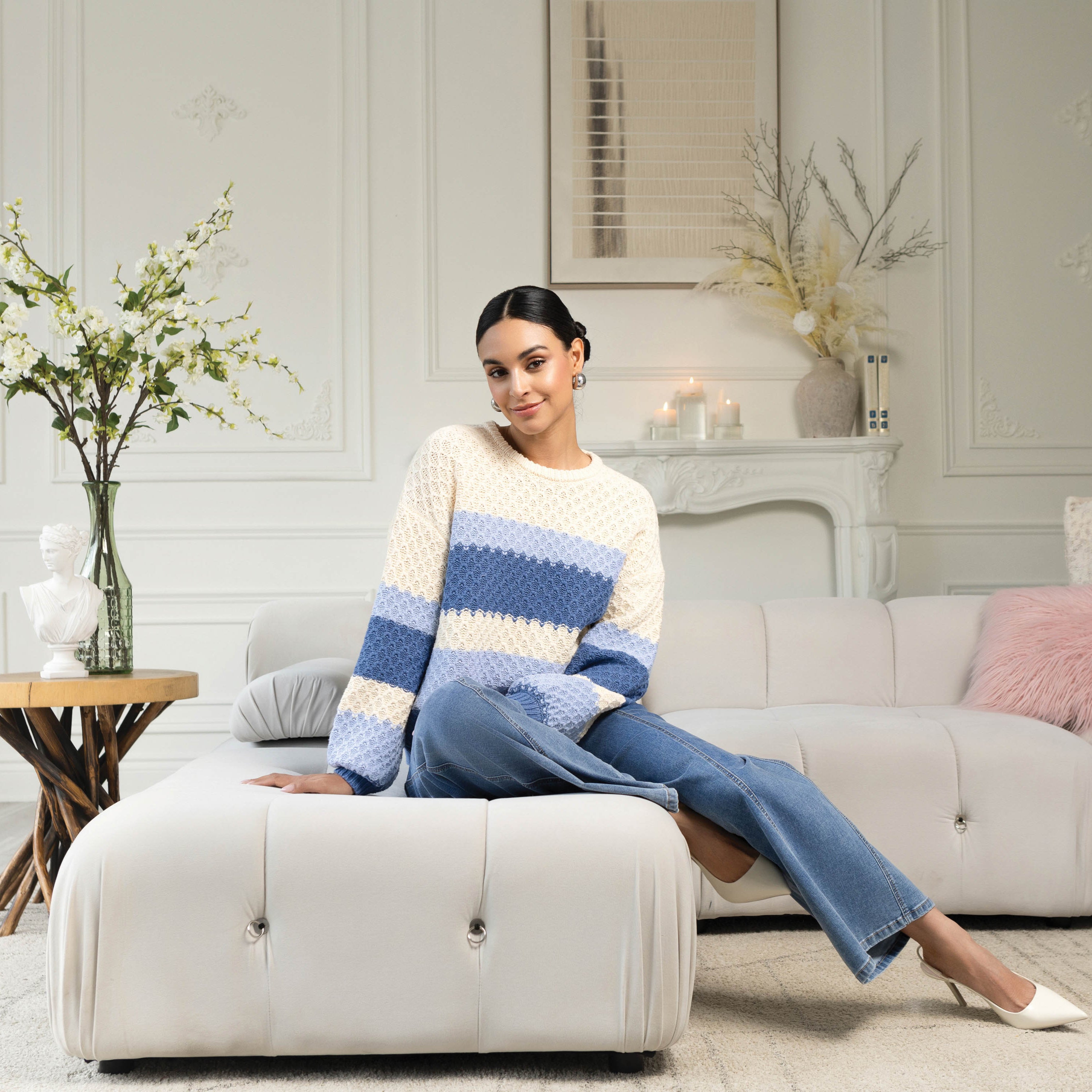Woman sitting on a white ottoman in a stylish living room.