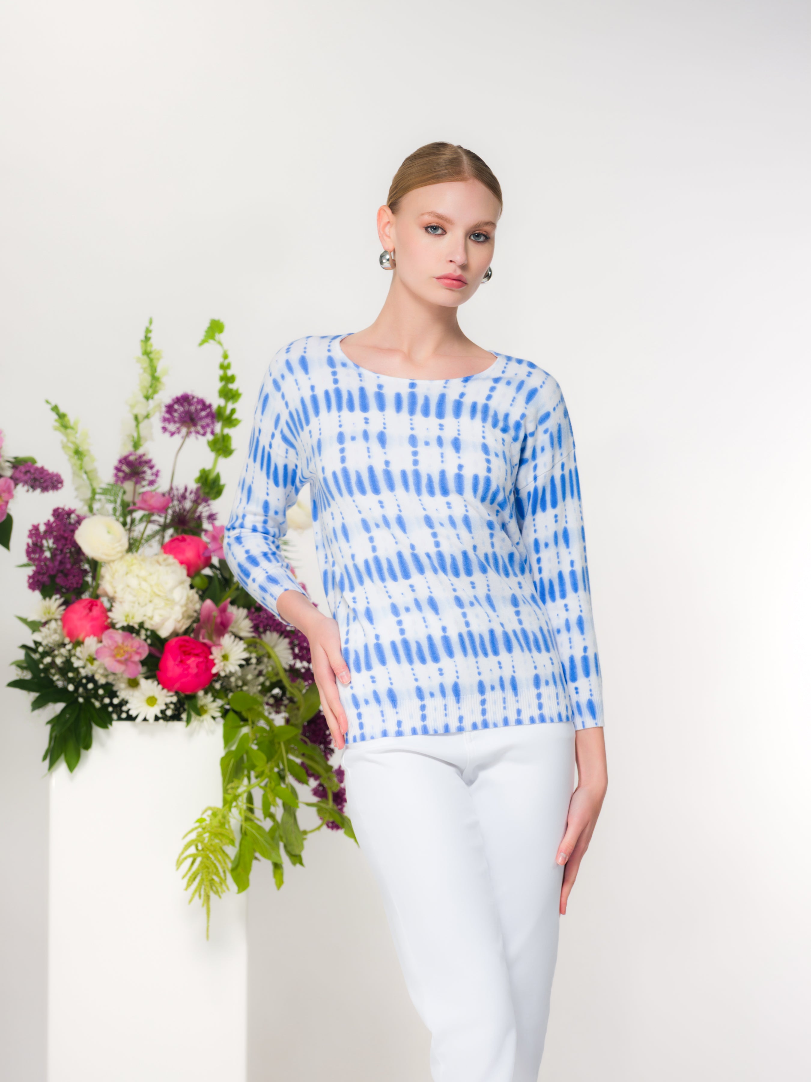 Model wearing a women’s long-sleeve knit pullover with a soft drape and classic neckline, styled for an everyday polished look.