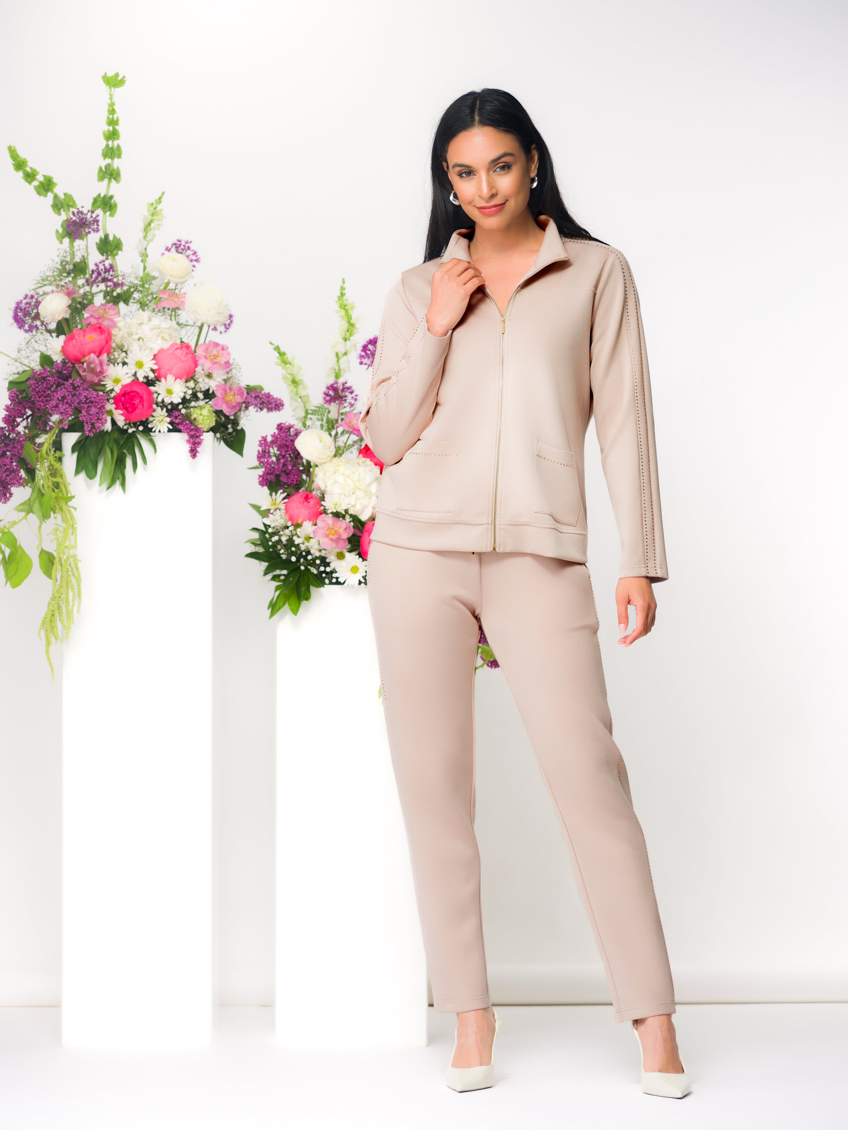 Women’s zip-front cardigan top with a structured silhouette and matching slim-fit pants, shown on a model standing indoors with natural light and florals.