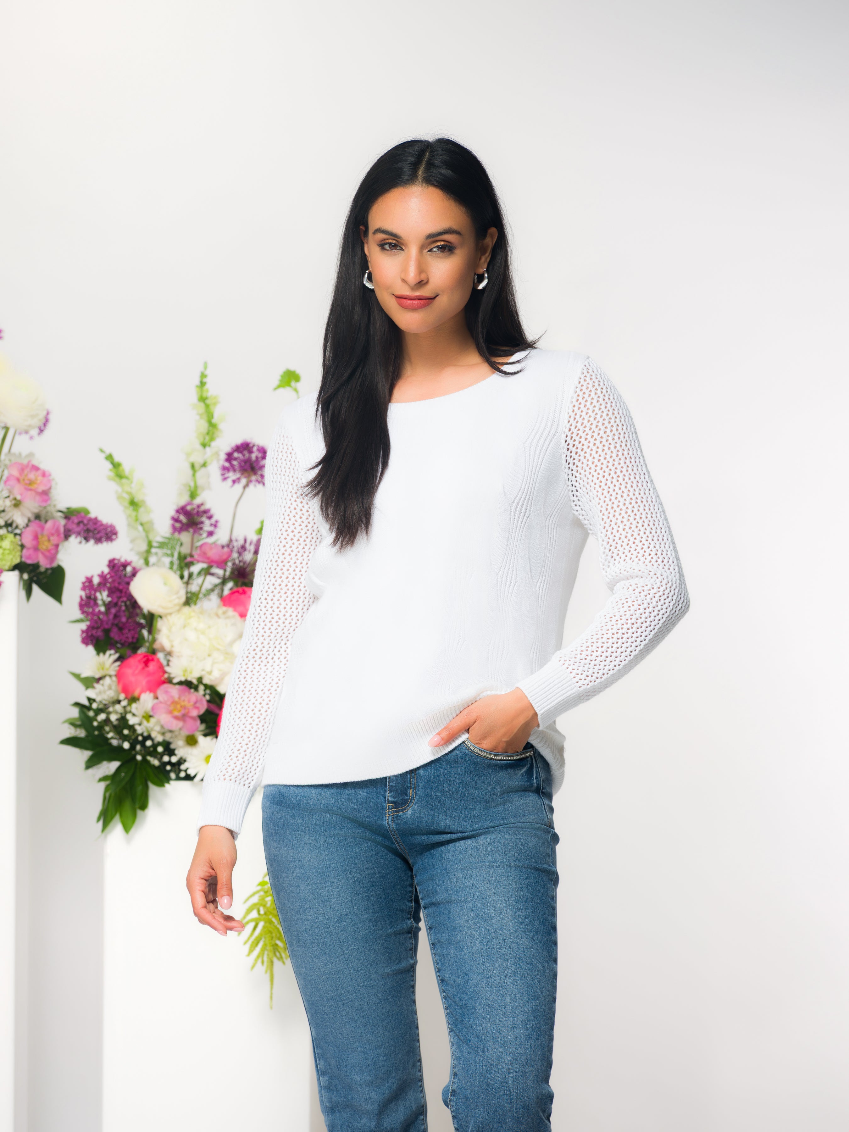 Women’s long-sleeve sweater with a crew neckline and open-knit sleeve detailing, styled with classic jeans on a model in a studio setting.