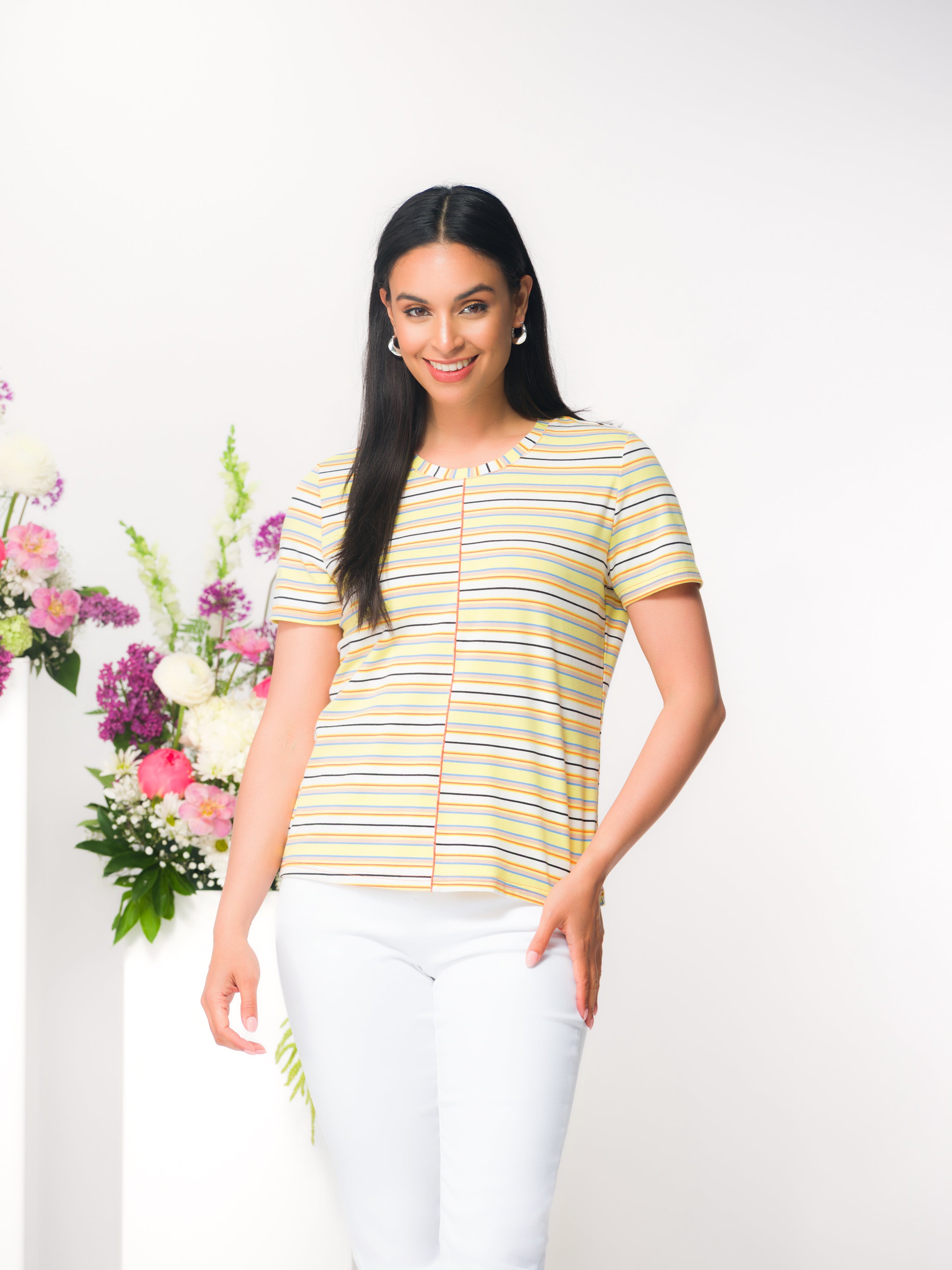 Woman wearing a relaxed-fit short-sleeve knit tee with a classic crew neckline, styled with fitted pants in a studio setting.