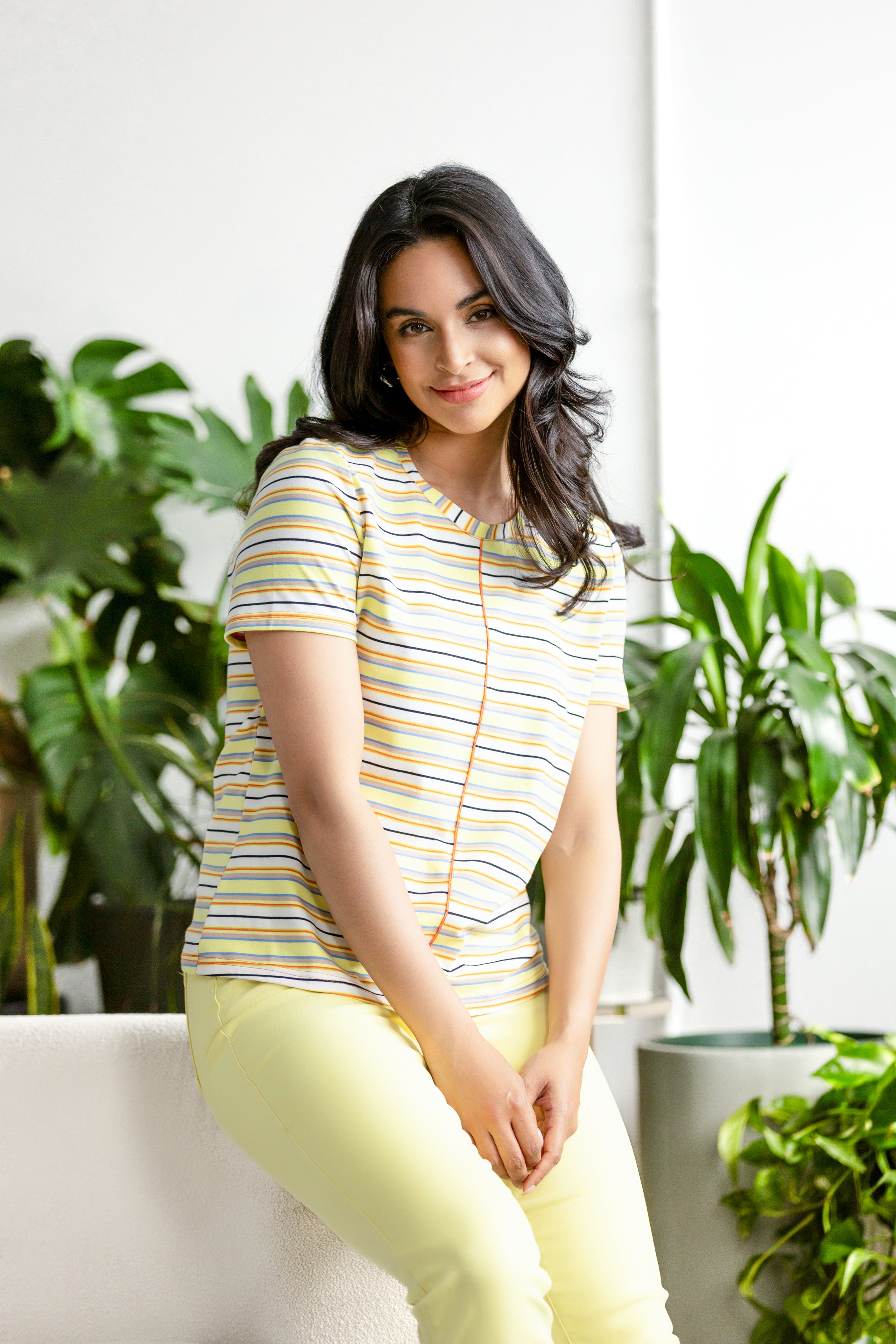 Woman wearing a relaxed-fit short-sleeve knit tee with a classic crew neckline, styled with fitted pants in a studio setting.