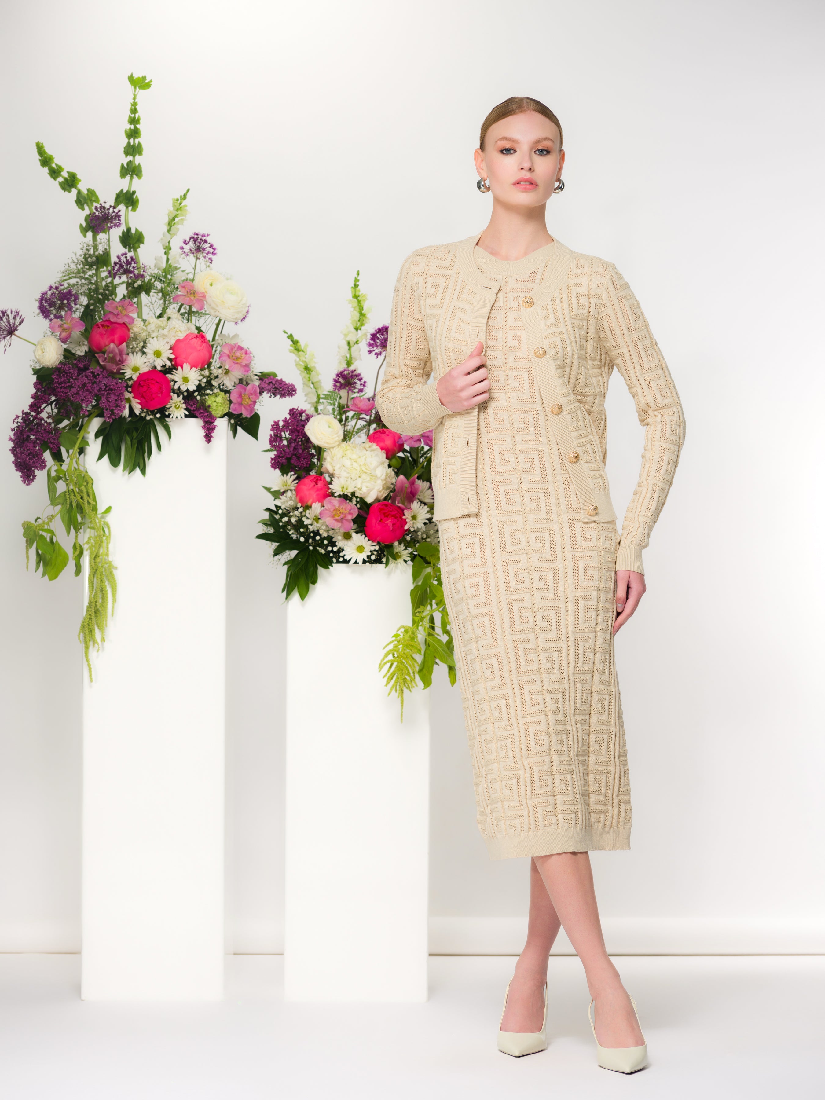 Woman wearing a textured knit cardigan and matching skirt, styled with a classic silhouette and button-front design, photographed in a studio setting.