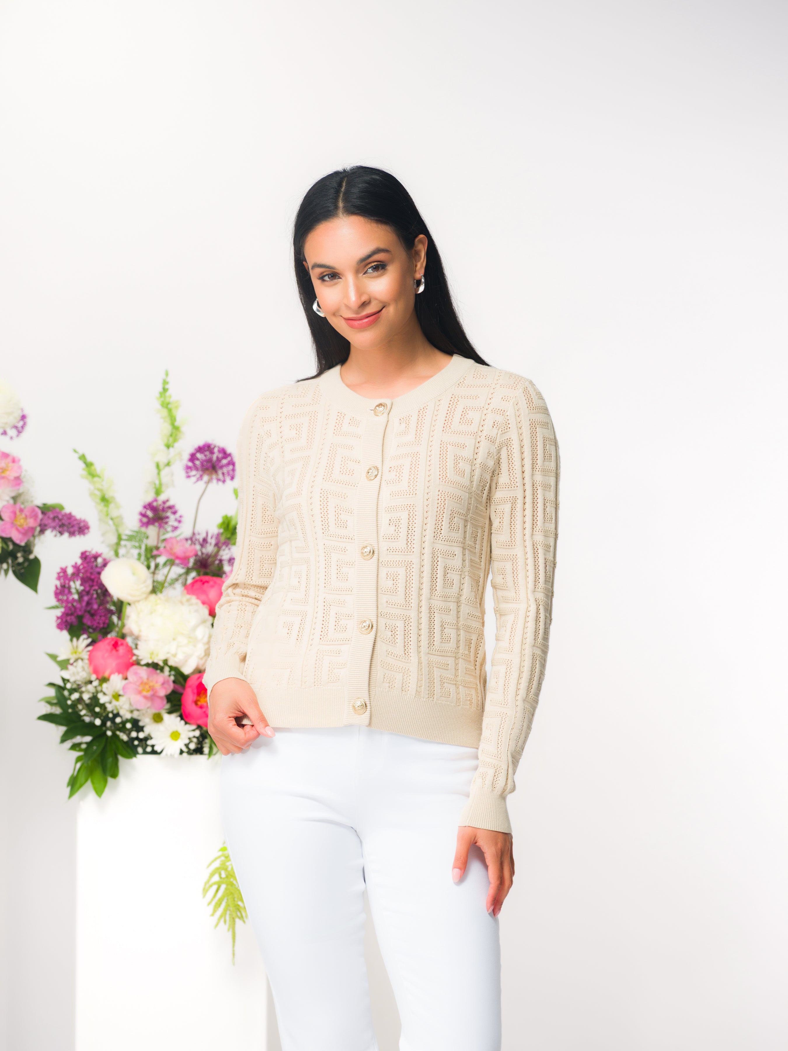 Woman wearing a textured knit button-front cardigan with a crew neckline, shown styled casually with trousers in a studio setting.