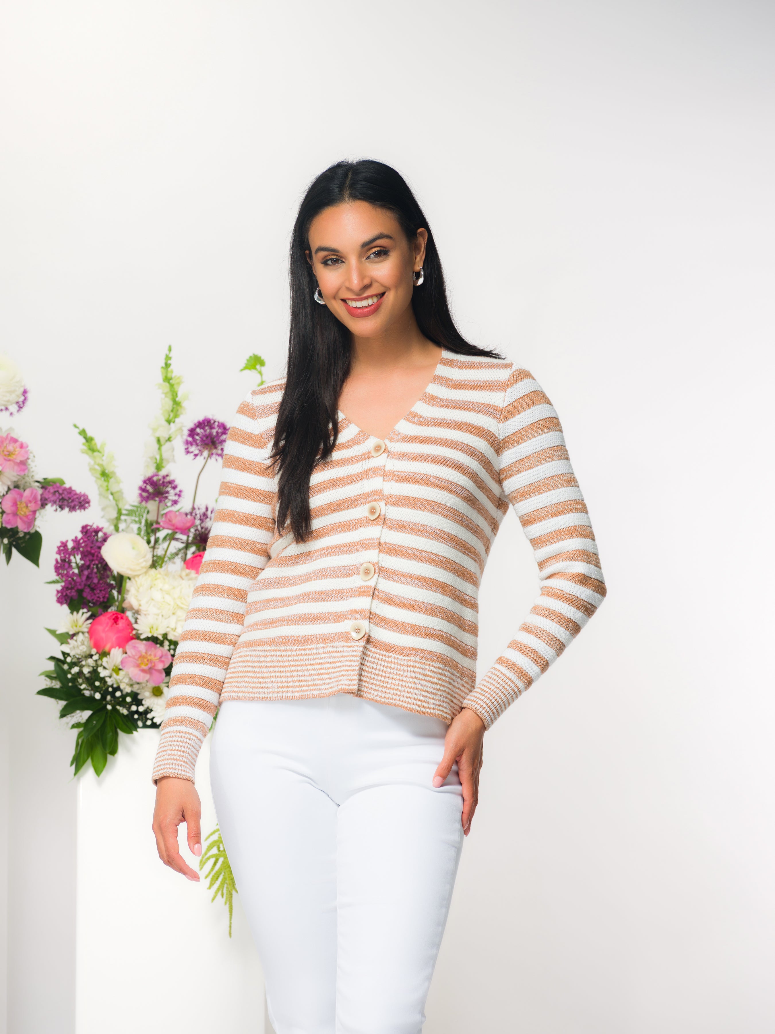 Women’s striped V-neck button-front knit cardigan in beige and white with subtle shimmer, long sleeves, and ribbed trim, styled with light grey fitted pants.