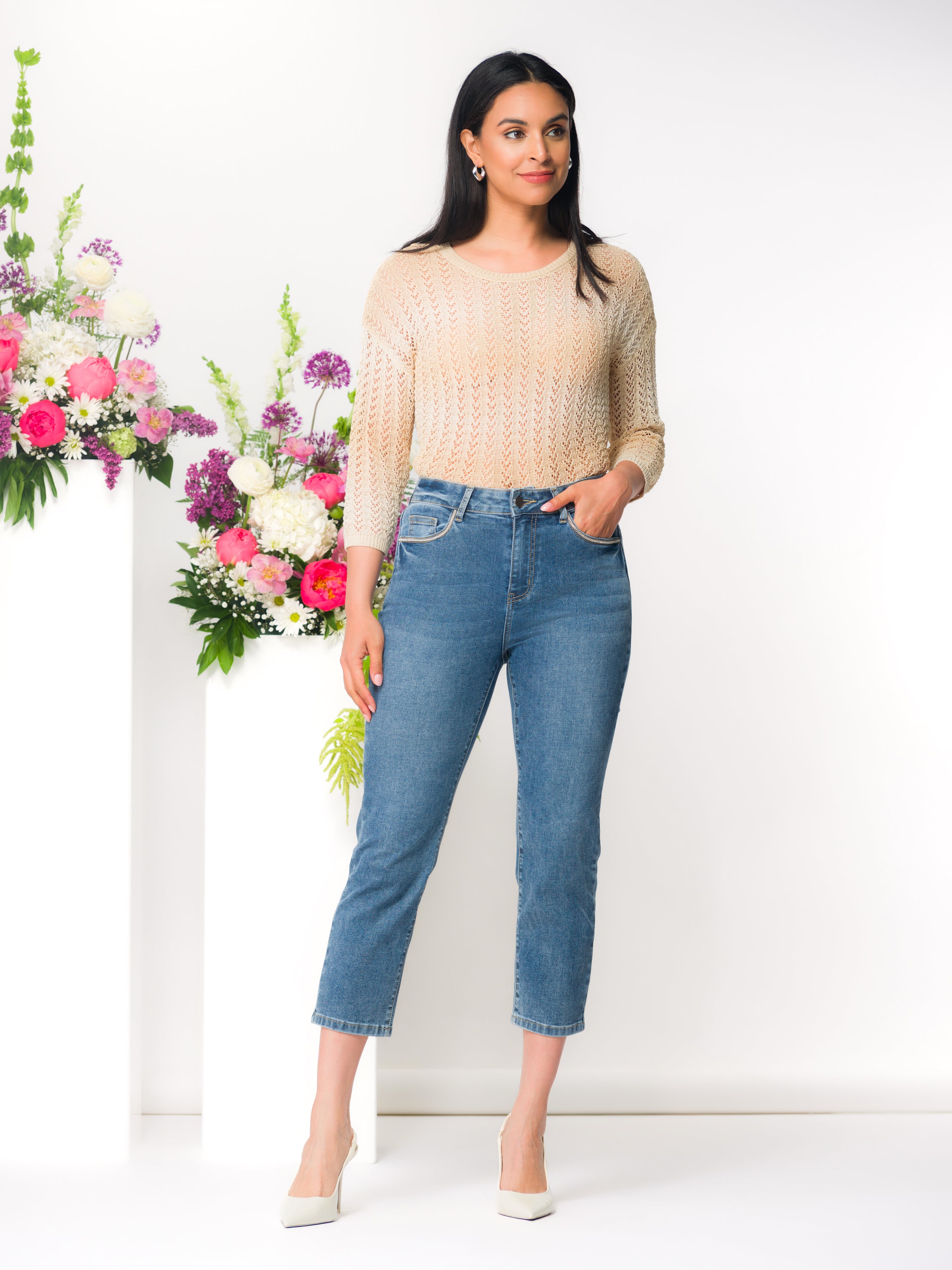 Women’s high-rise slim capri jeans in medium blue wash with five-pocket styling, fitted through the hip and thigh, styled with a lightweight knit top and heels.
