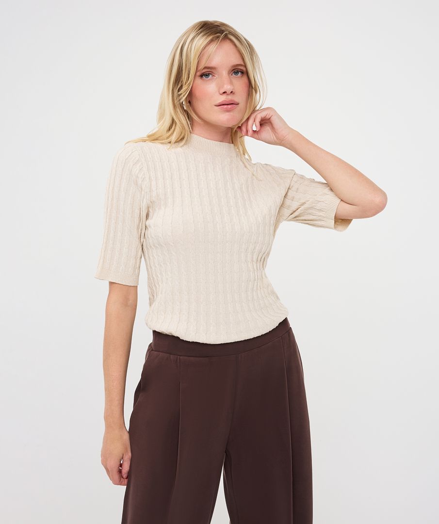 Woman modelling an ivory ribbed knit short-sleeve top with a high neckline and fitted silhouette, shown from the front.