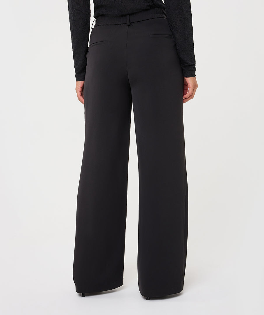 Model wearing black wide-leg trousers