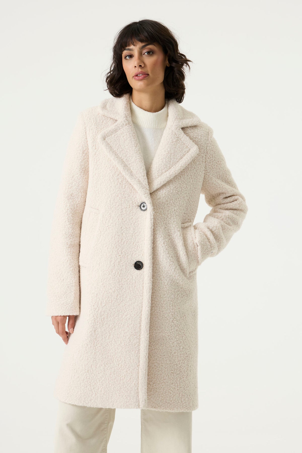 Woman wearing a cream Lennox Textured Coat with notched lapels, button front and side pockets.