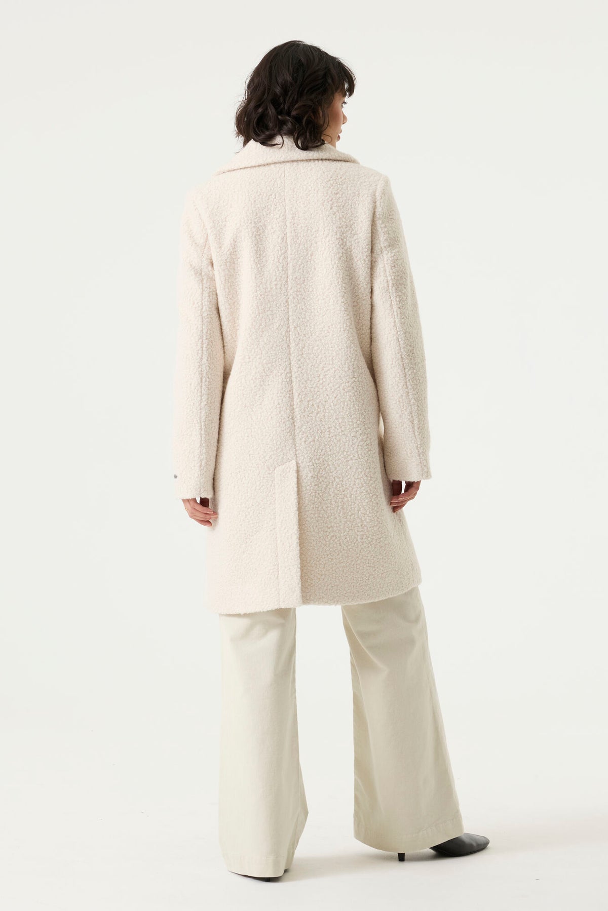 Woman wearing a cream Lennox Textured Coat with notched lapels, button front and side pockets.