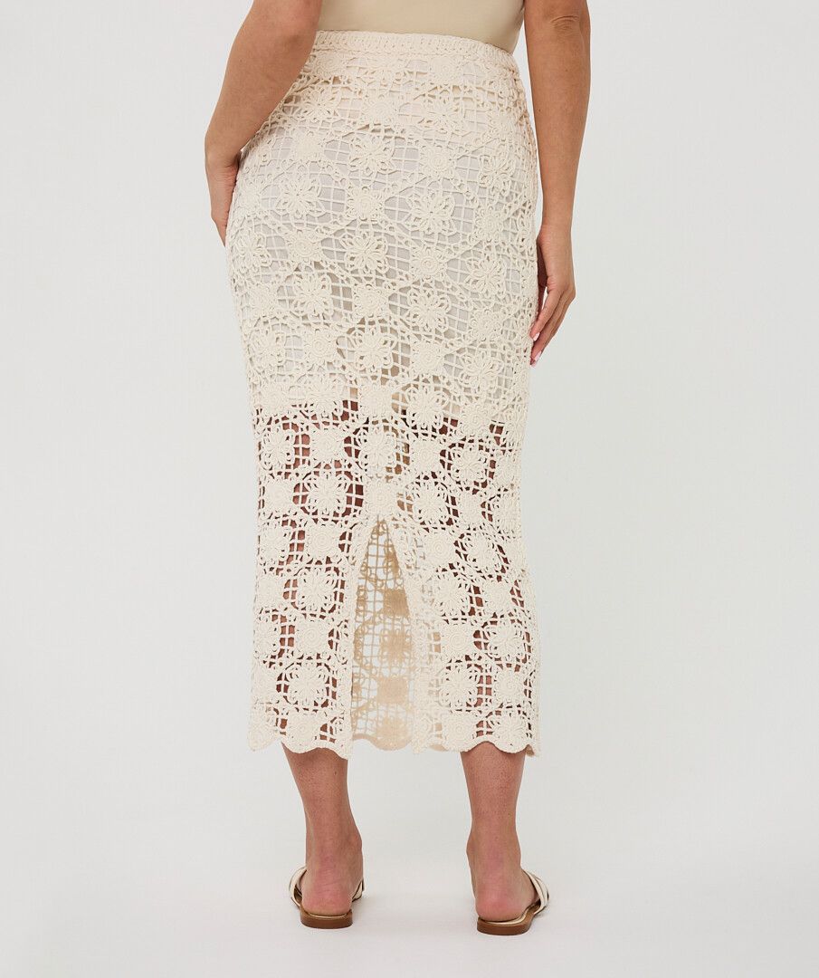 Back view of a cream crochet midi skirt with intricate openwork pattern, scalloped hem, and partial lining.