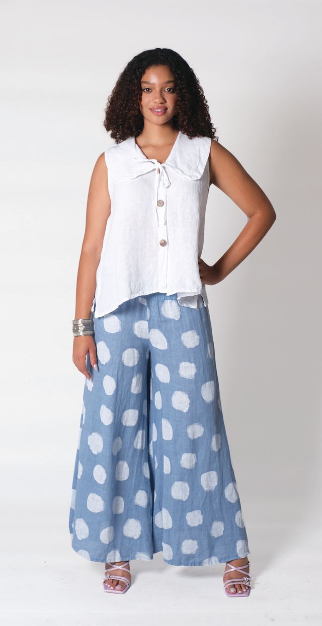 Model wearing polka dot linen pants with a white blouse, showcasing an airy and stylish summer outfit.