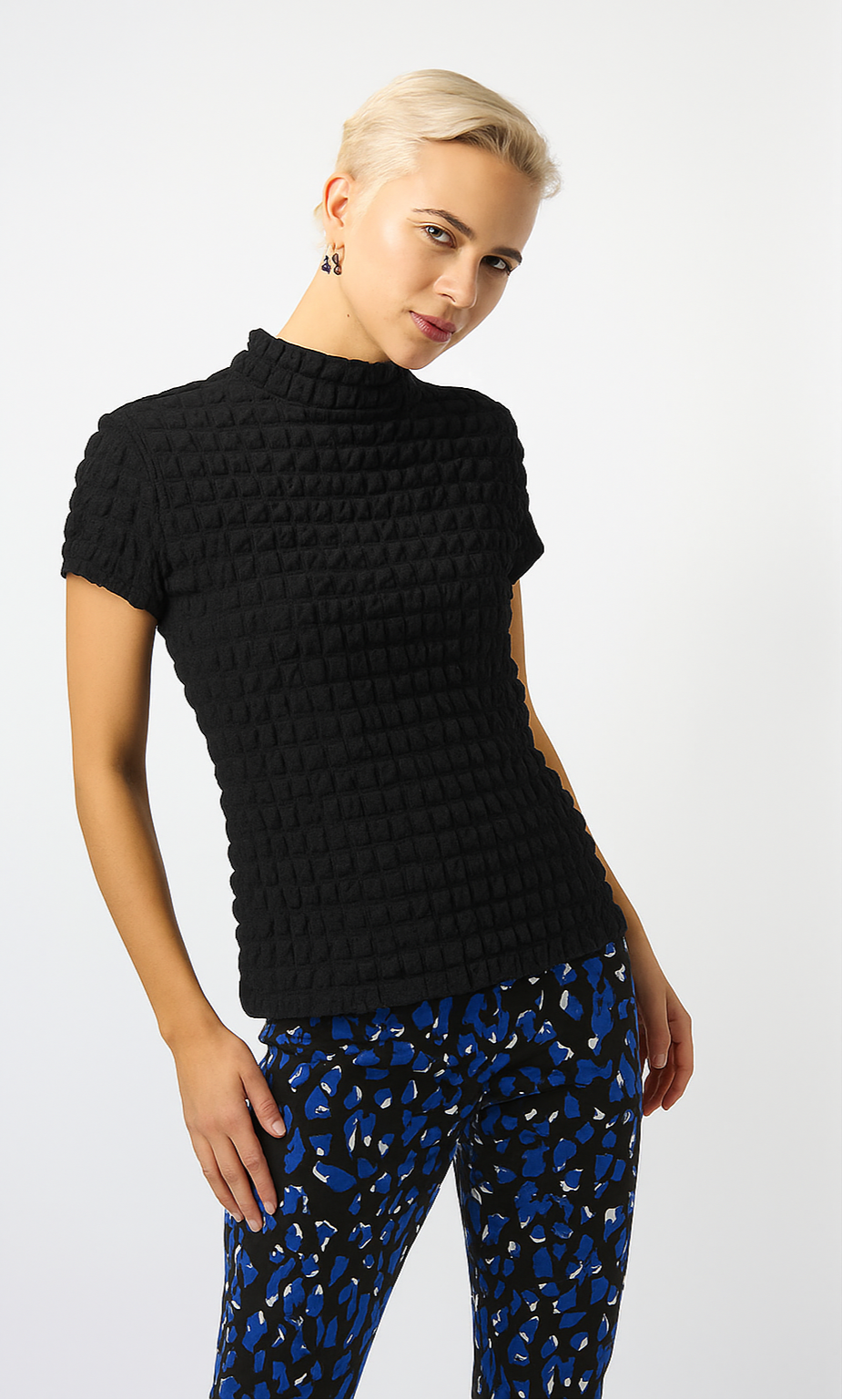 blonde woman wearing black textured top and blue patterned pants