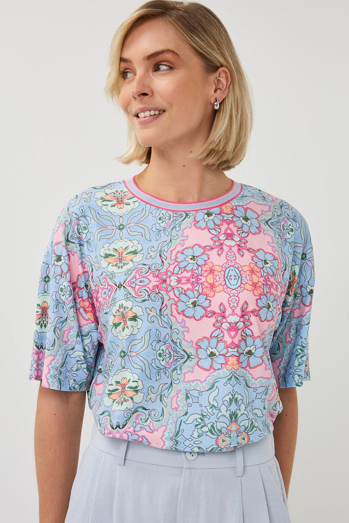 Woman wearing a floral patterned blouse against a plain background