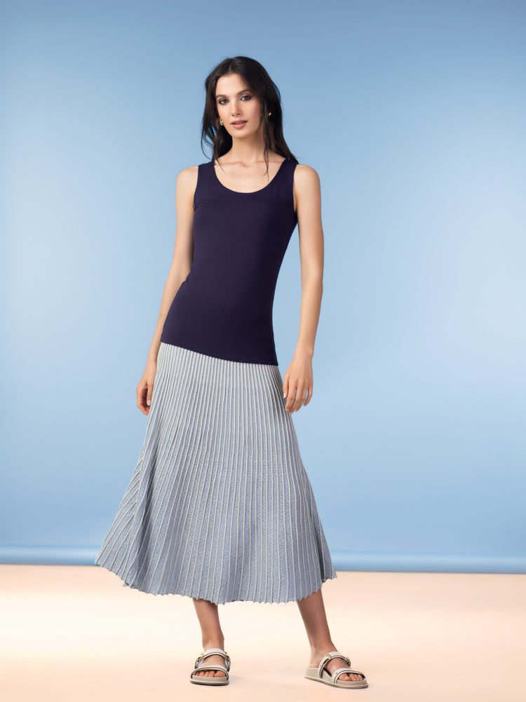 Woman wearing navy sleeveless tank top with grey pleated midi skirt.