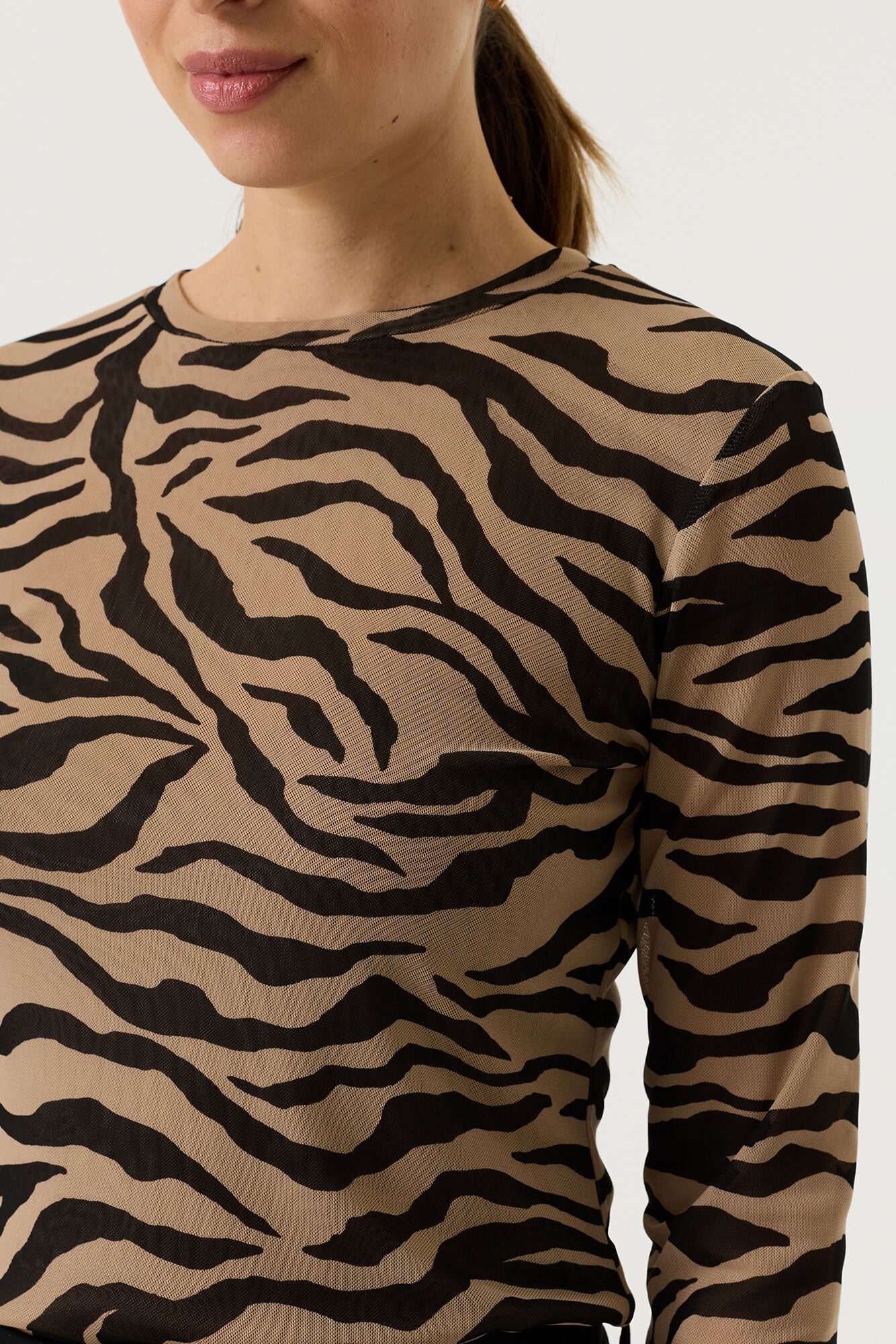 Close-up of a woman wearing a tan and black zebra-print long-sleeve top.