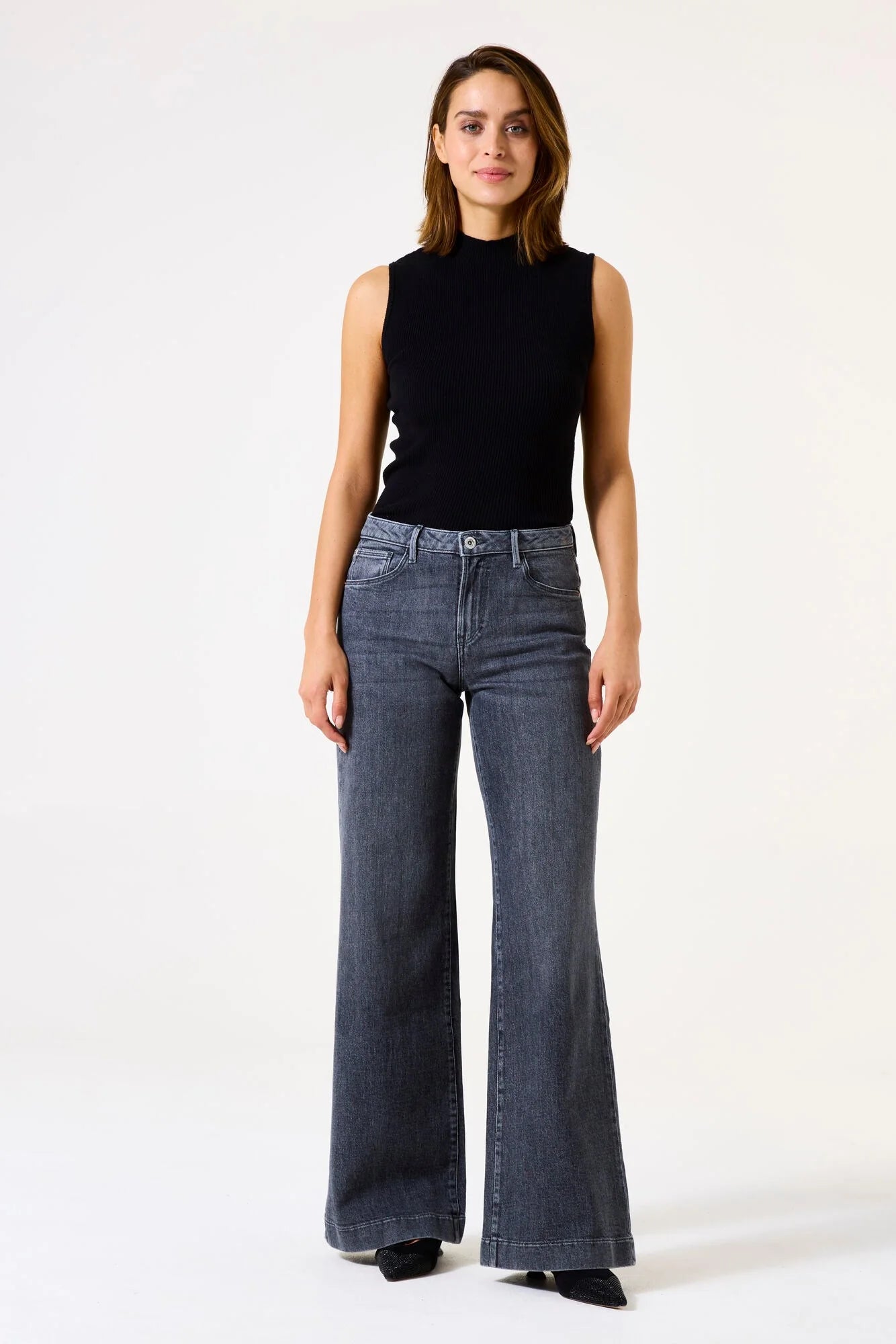 Women's ribbed mock neck sleeveless knit top with a flattering fitted shape and streamlined silhouette. Paired with wide-leg jeans for a polished casual look suitable for work, weekends, or layering.