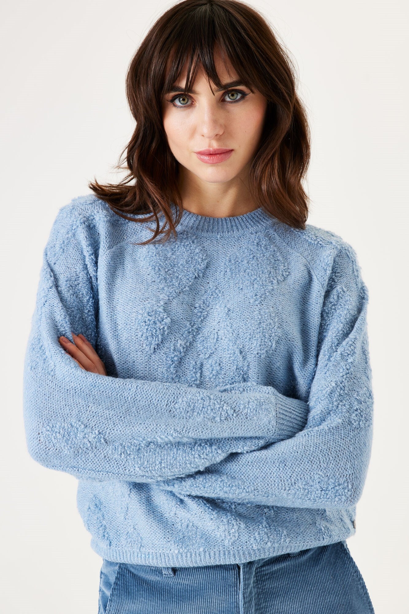 Woman wearing a light blue sweater against a white background