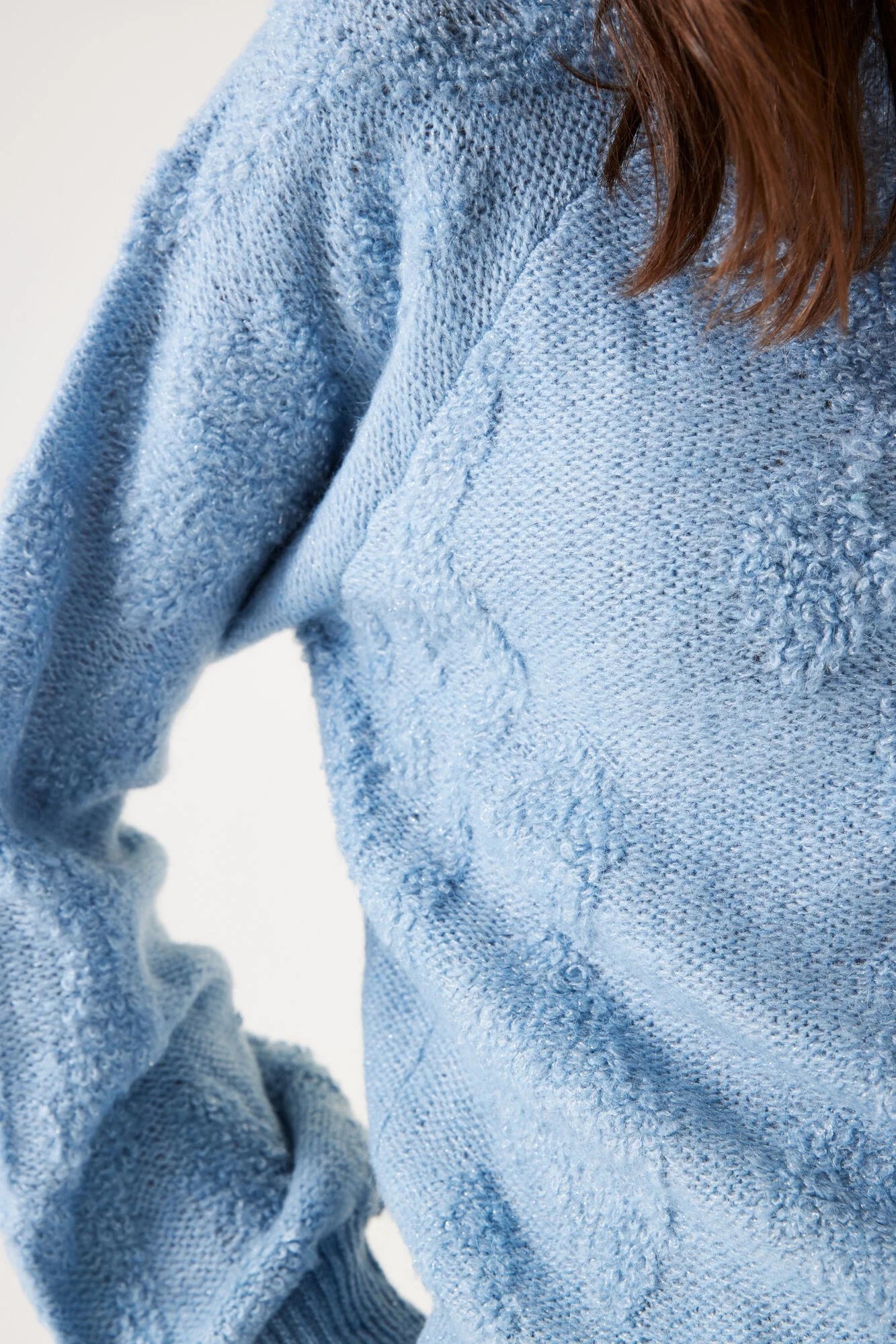 Close-up of a person wearing a textured blue sweater against a light background
