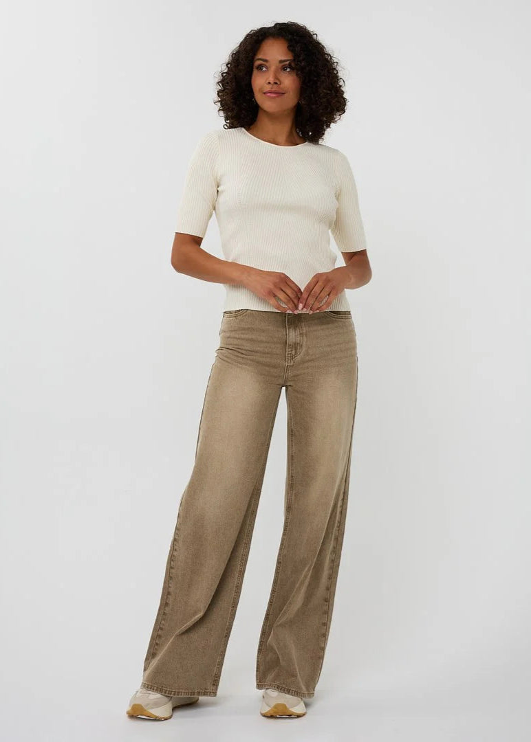 Woman wearing a white top and beige wide-leg pants on a white background