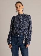 Woman wearing a navy printed button-front blouse with point collar, styled with dark wash jeans.